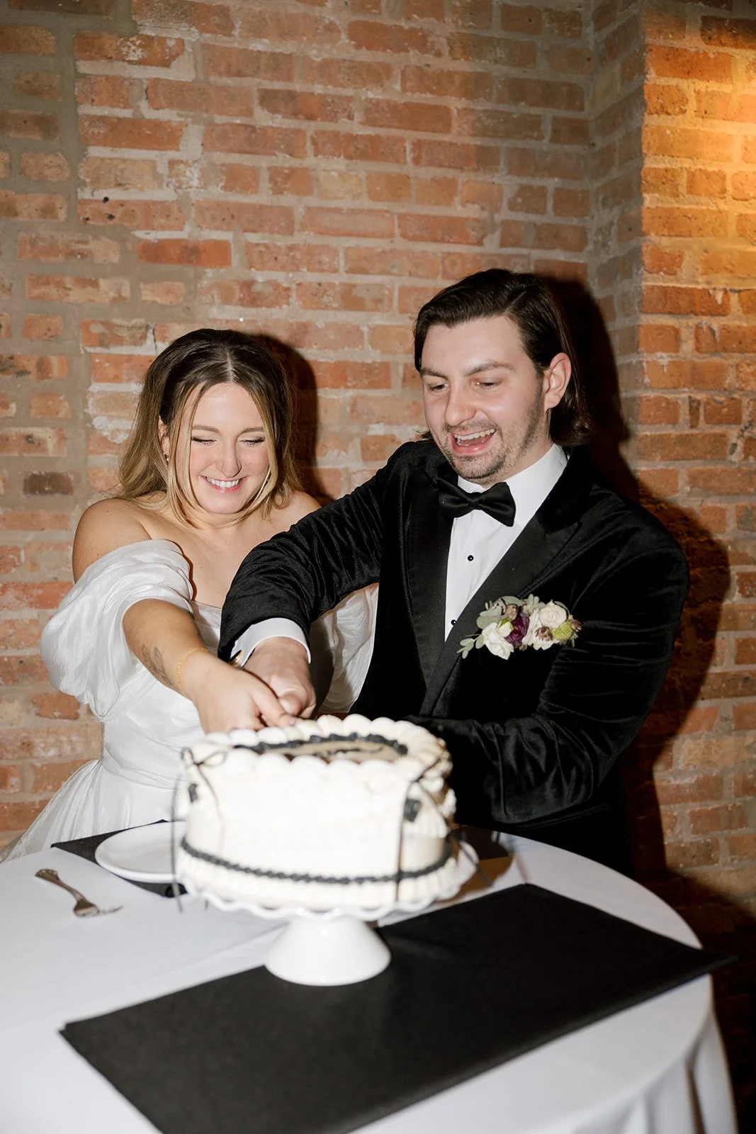 Bride and groom smiling while cutting cake at wedding reception