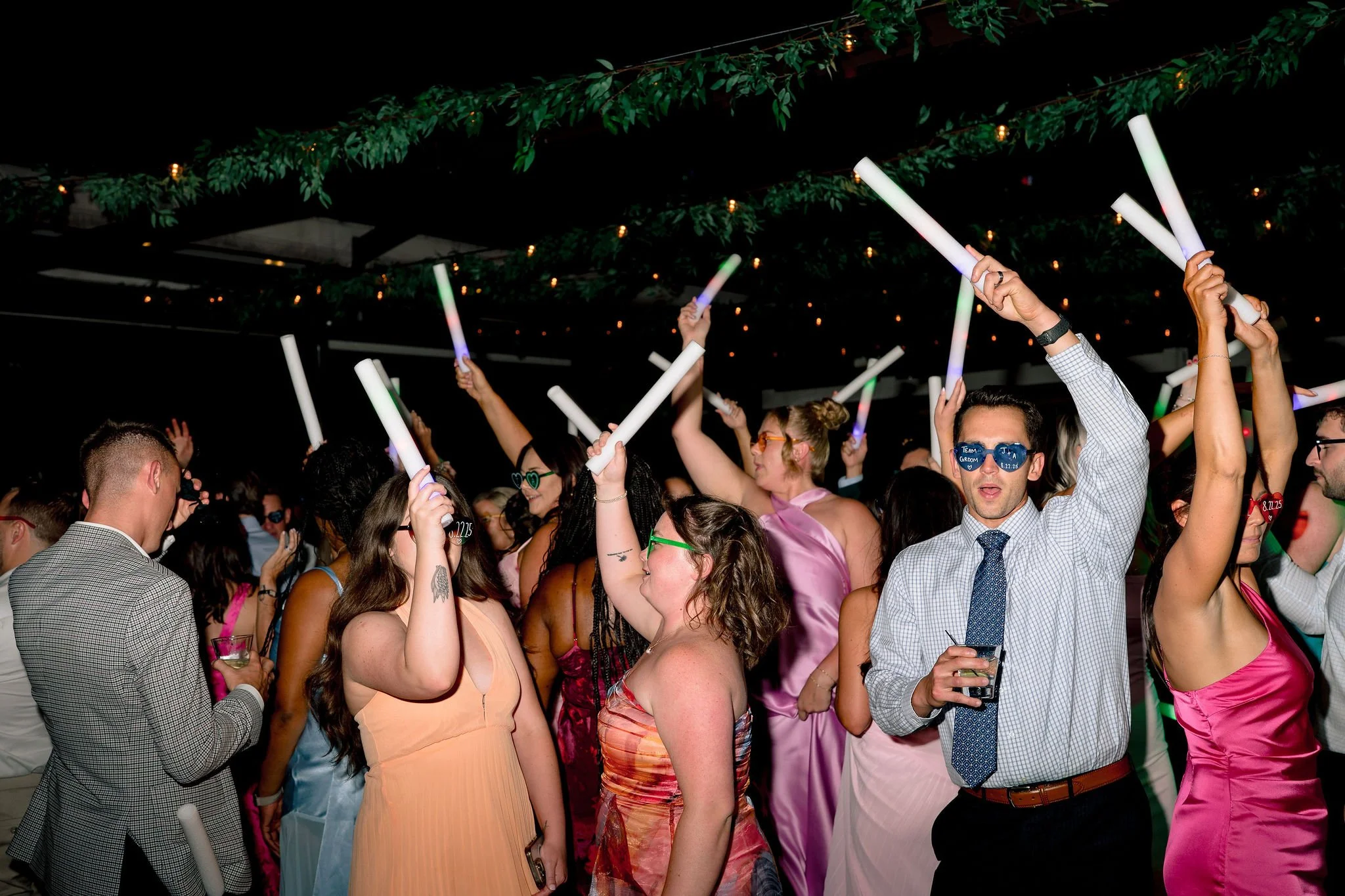 wedding guests dancing with LED foam glow sticks waving in the air flash photo