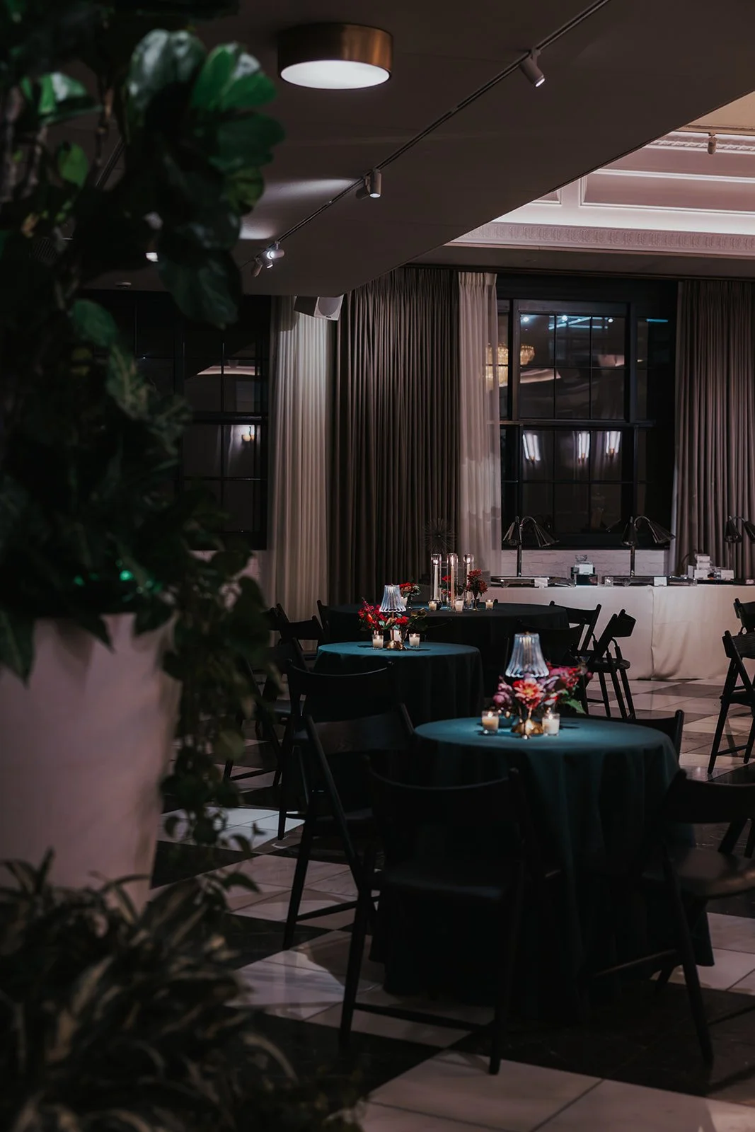 great gatsby inspired wedding with dark green linens and red florals moody lighting for wedding reception