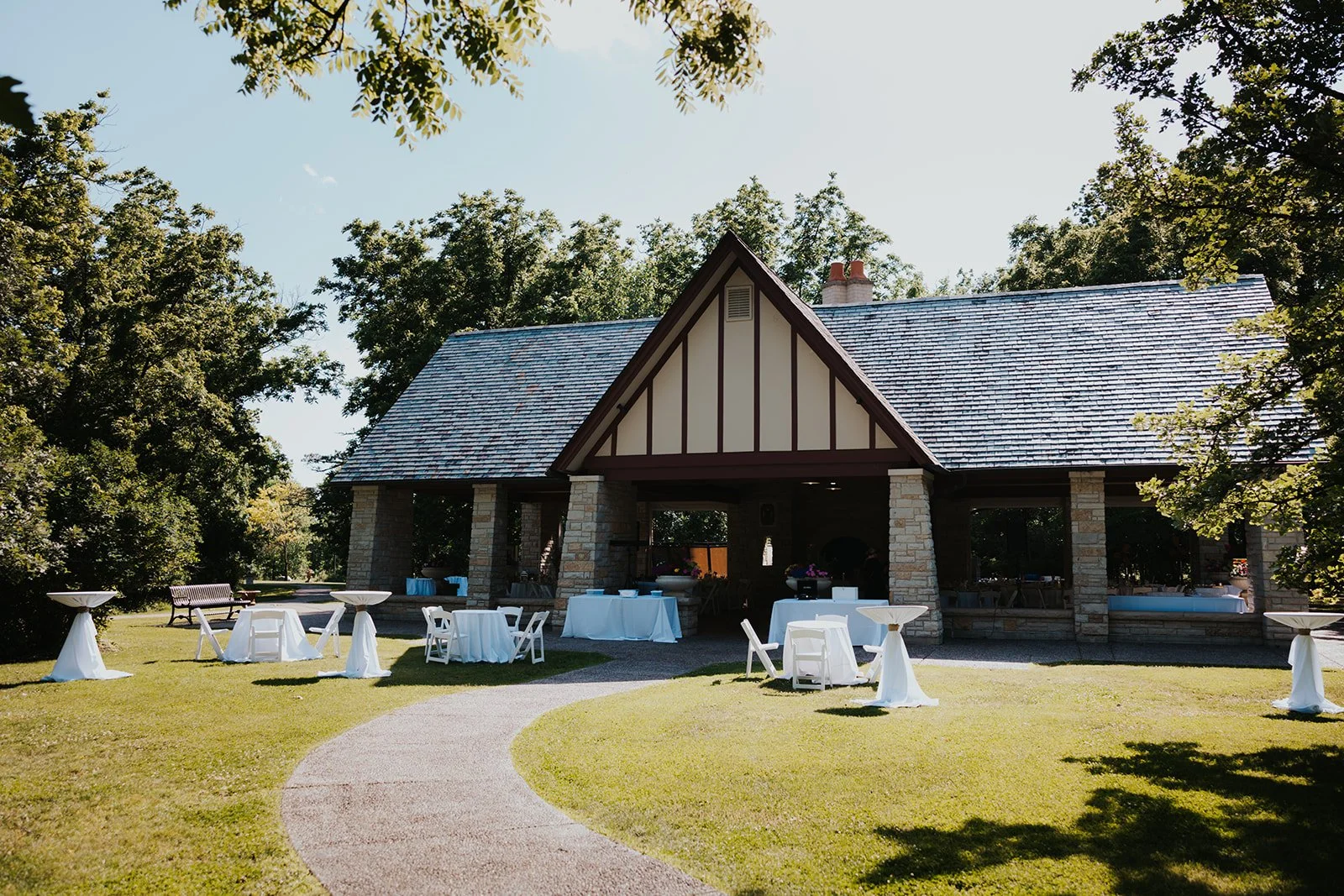 Full shot of pavilion for outdoor covered reception with tables and chairs scattered in front of it