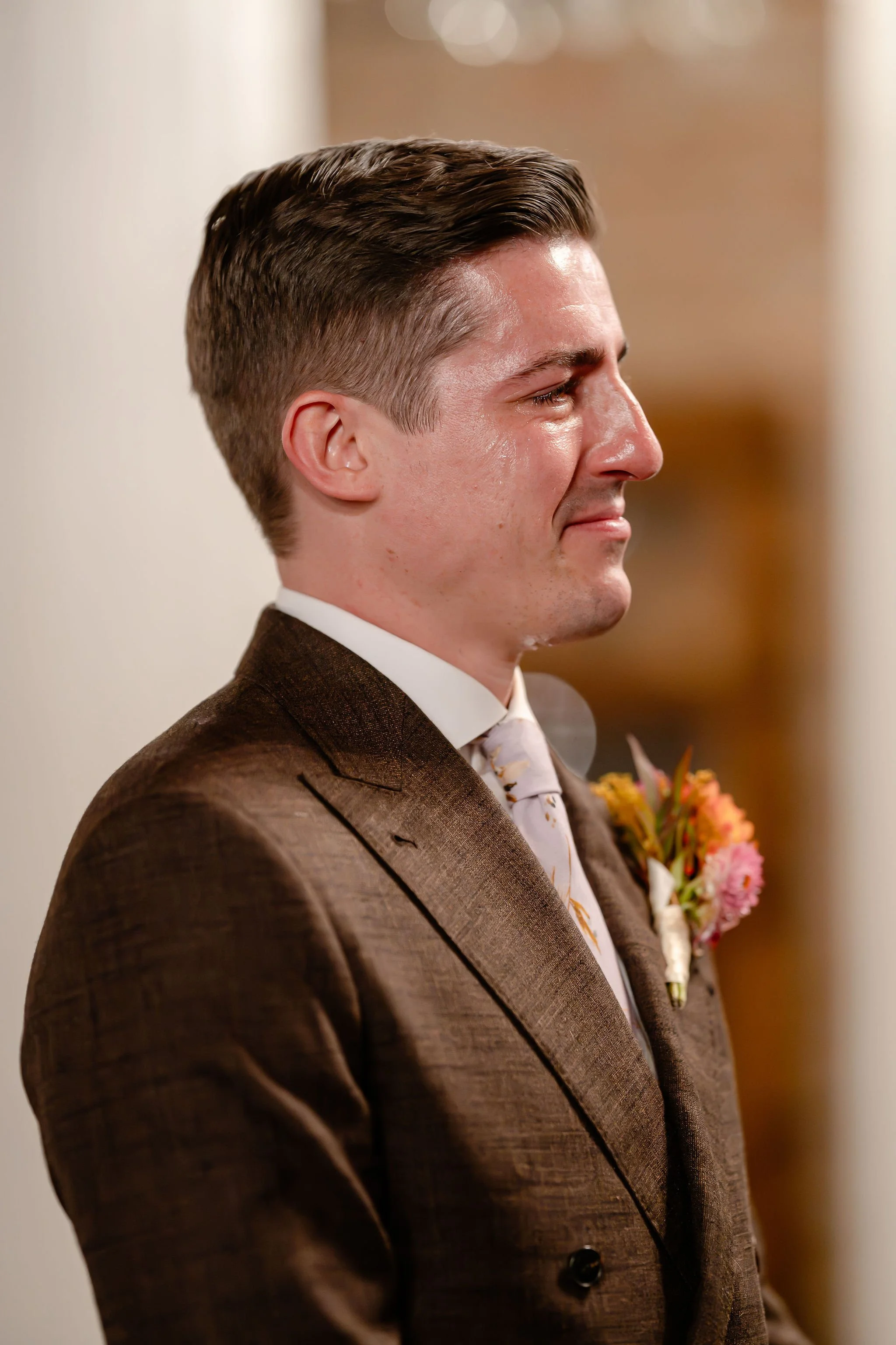 Groom in brown suit closeup of him failing to hold back tears streaming down face