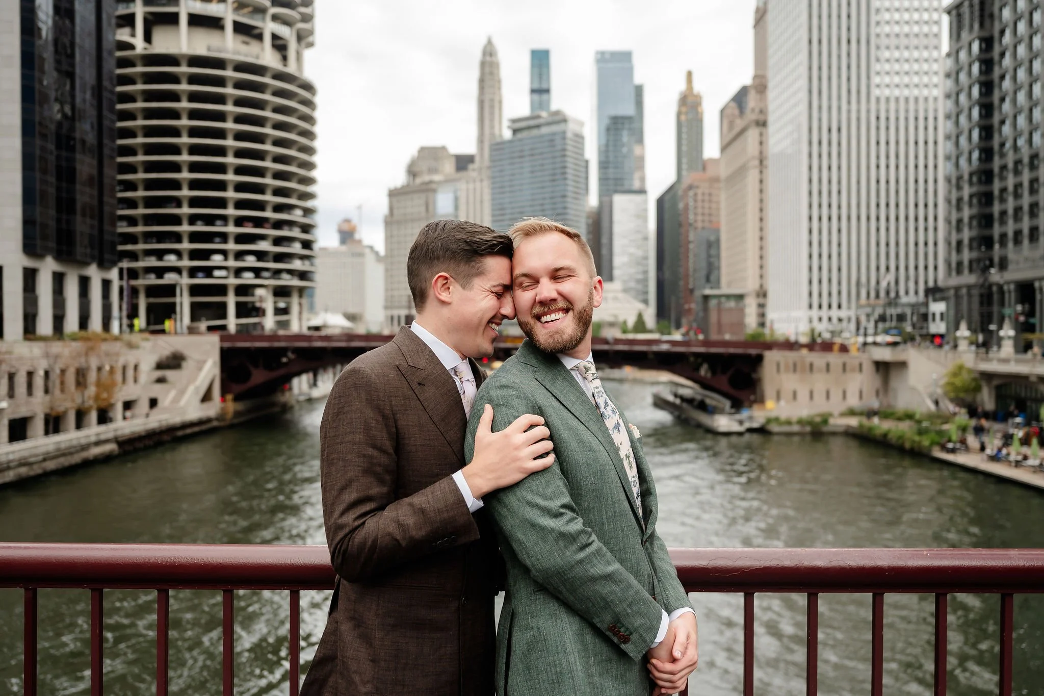 two grooms standing next to each other with river of Chicago as background