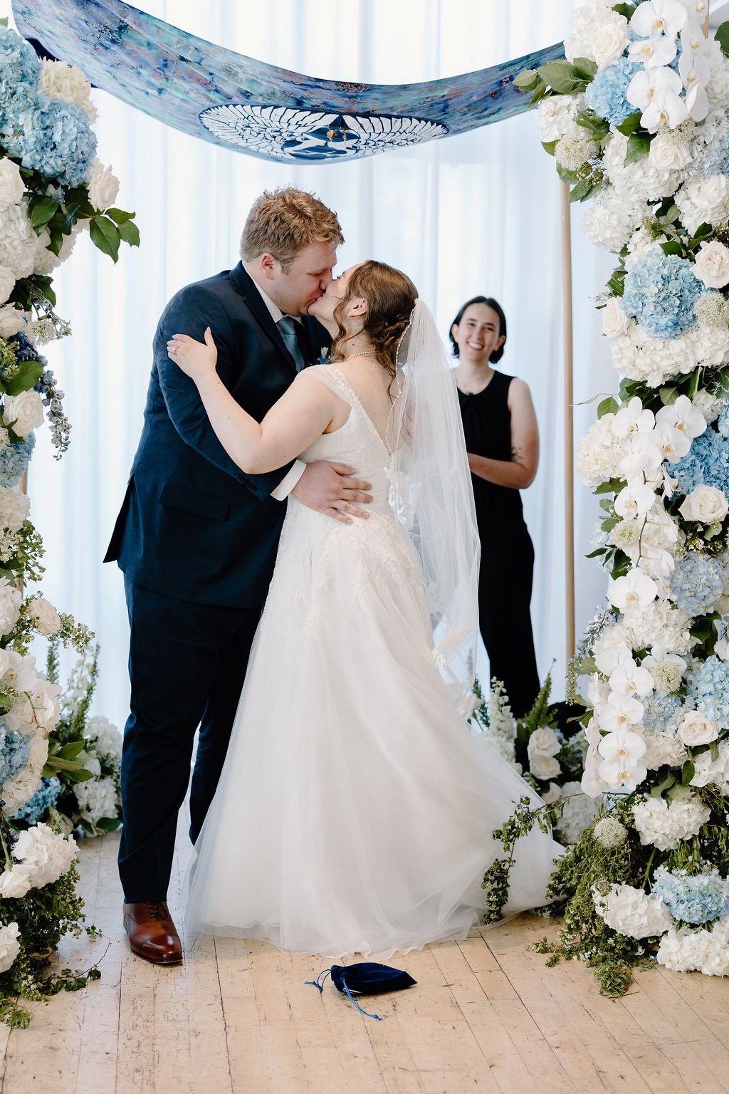 Bride and groom first kiss at wedding ceremony under chuppah