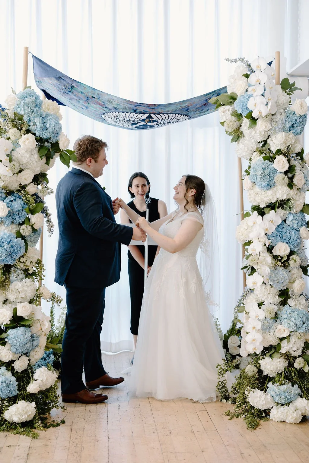 Bride and groom holding hands and smiling at Jewish wedding ceremony