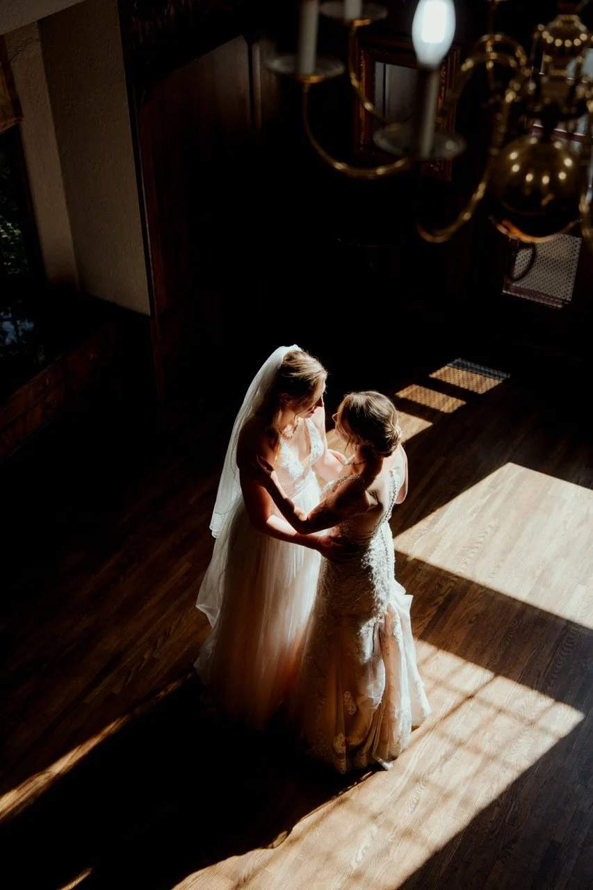 Two brides standing on wood floor below with sunny light and dark shadows all over