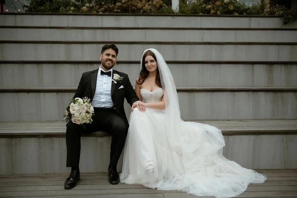 Bride and groom sitting on benches with hands on bride's leg