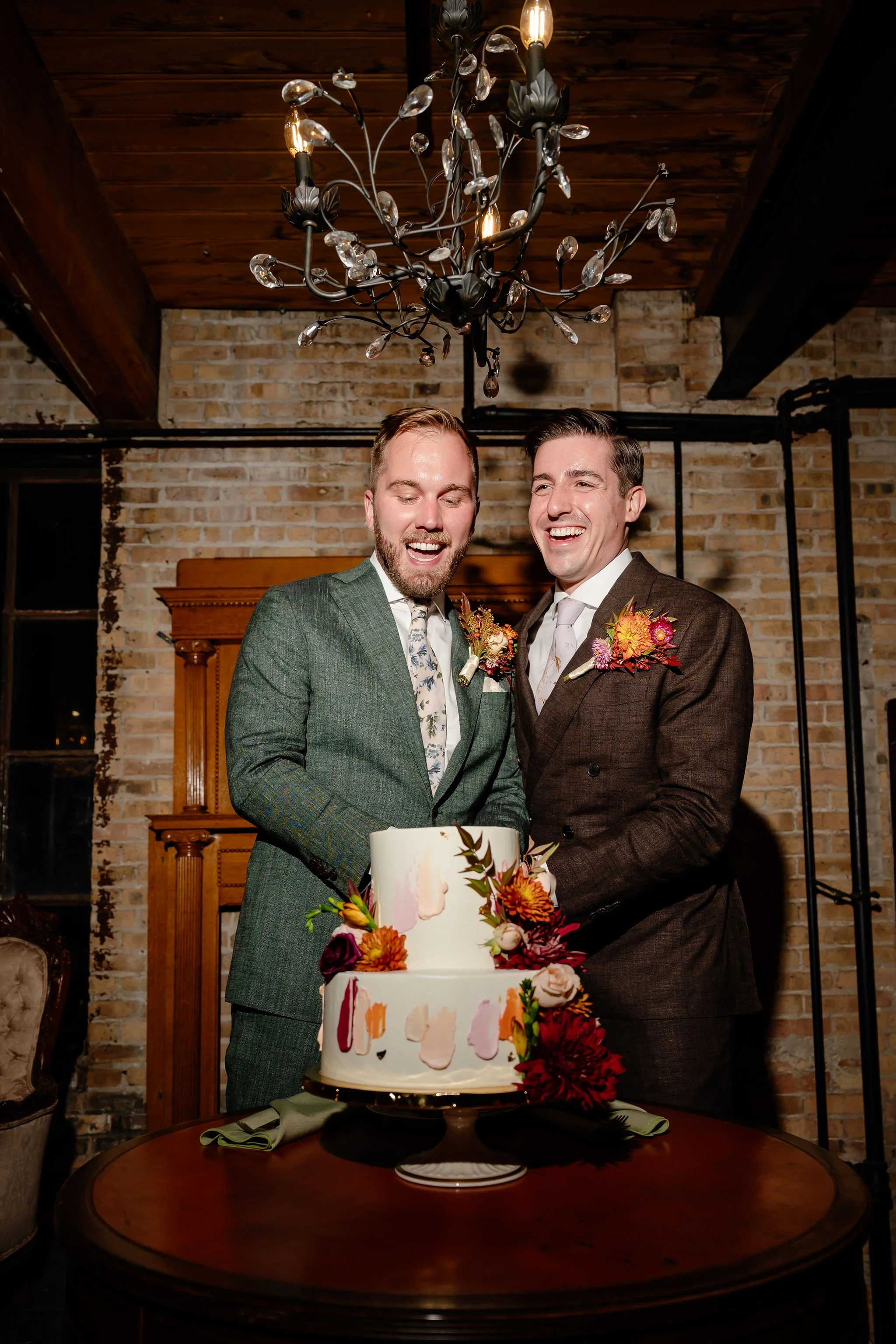 Two grooms smiling while cutting the cake