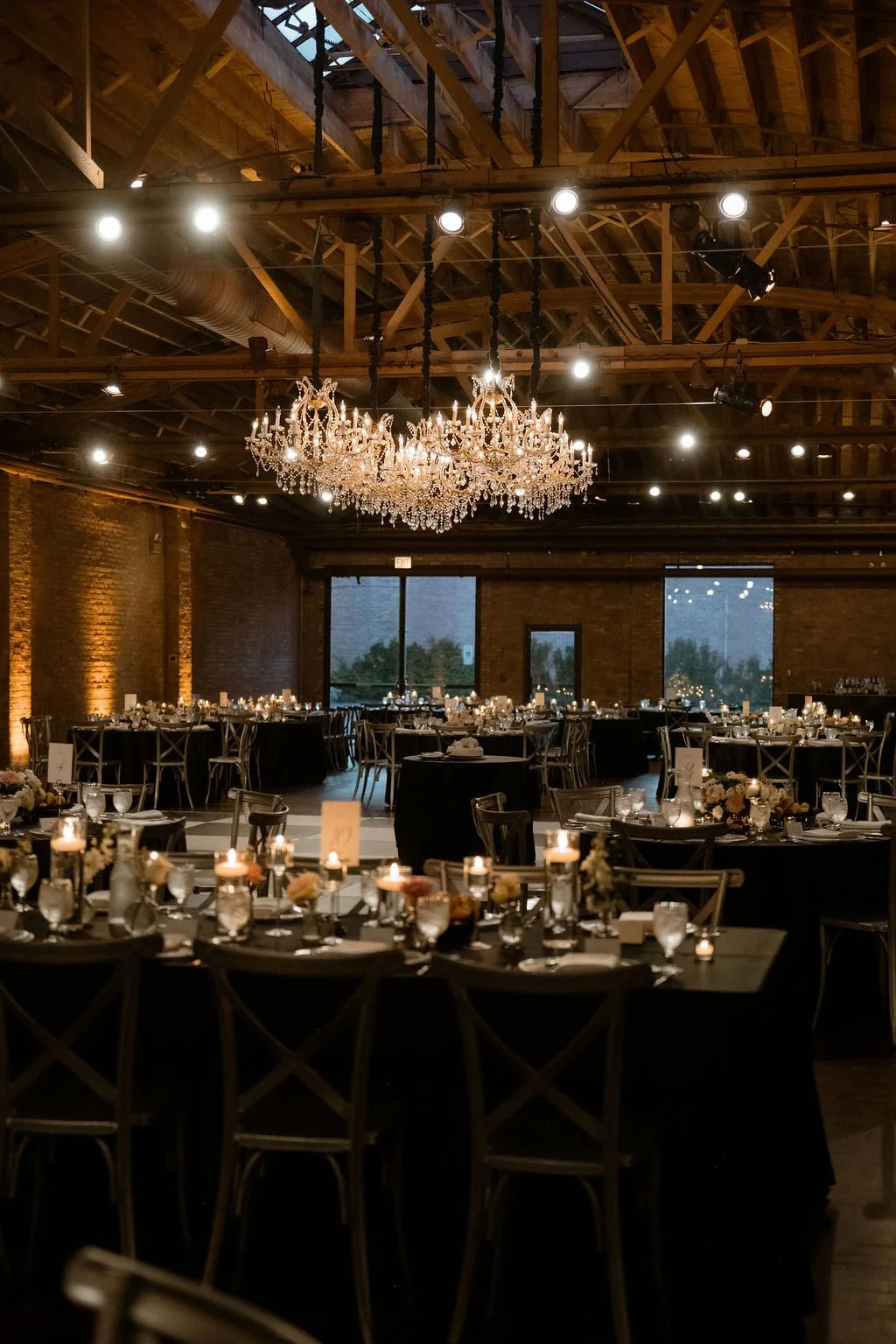 romantic lighting in warm wedding reception with black linens and lots of candles and bud vase flowers