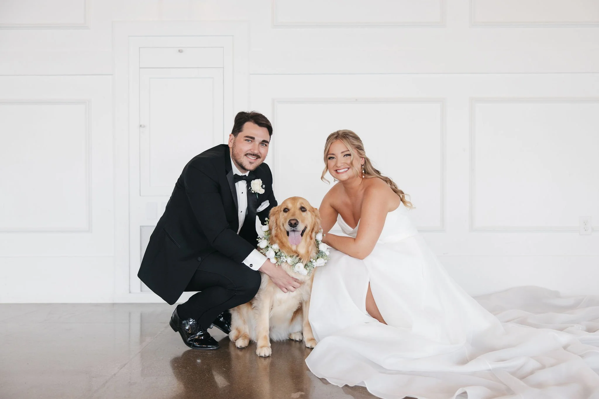 bride and groom crouched down with golden retriever dog in the middle all looking at camera and smiling