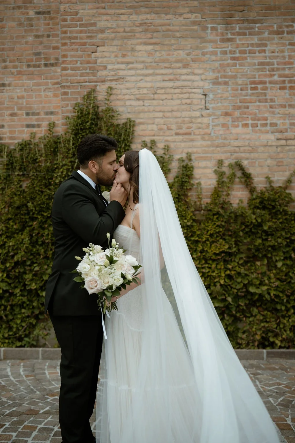 Wedding at Rockwell on the River bride and groom kissing outside with ivy brick wall as background