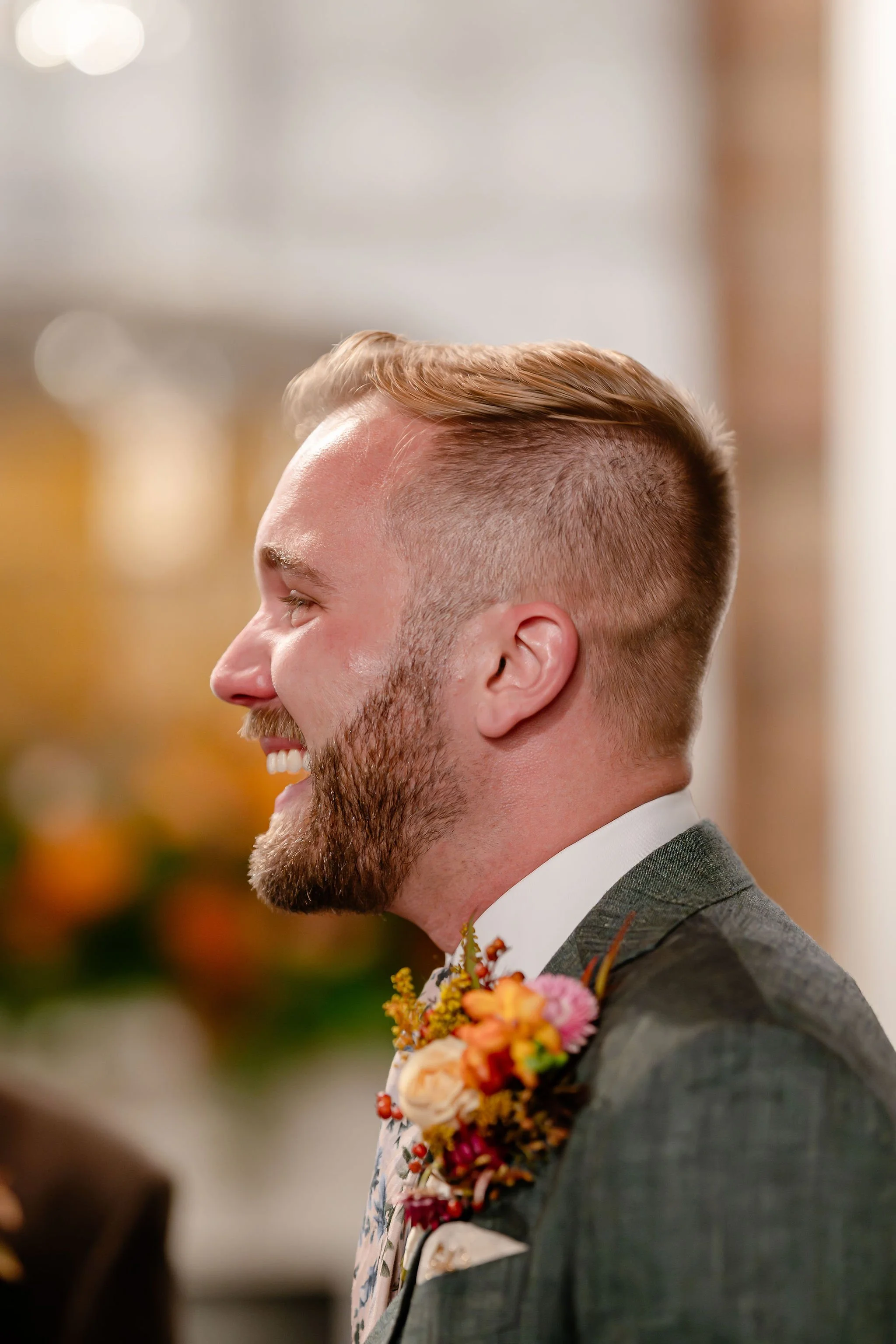 Groom in green suit closeup laughing while teary-eyed