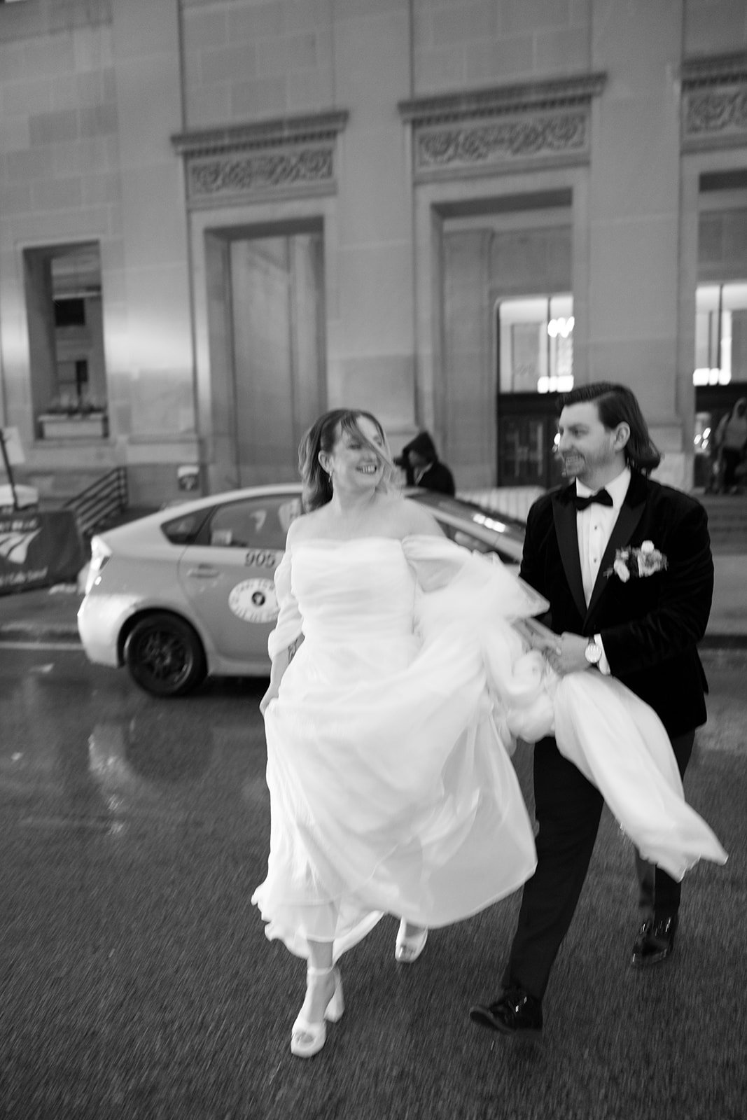 Couple blurry walking outside in street with car and people behind them