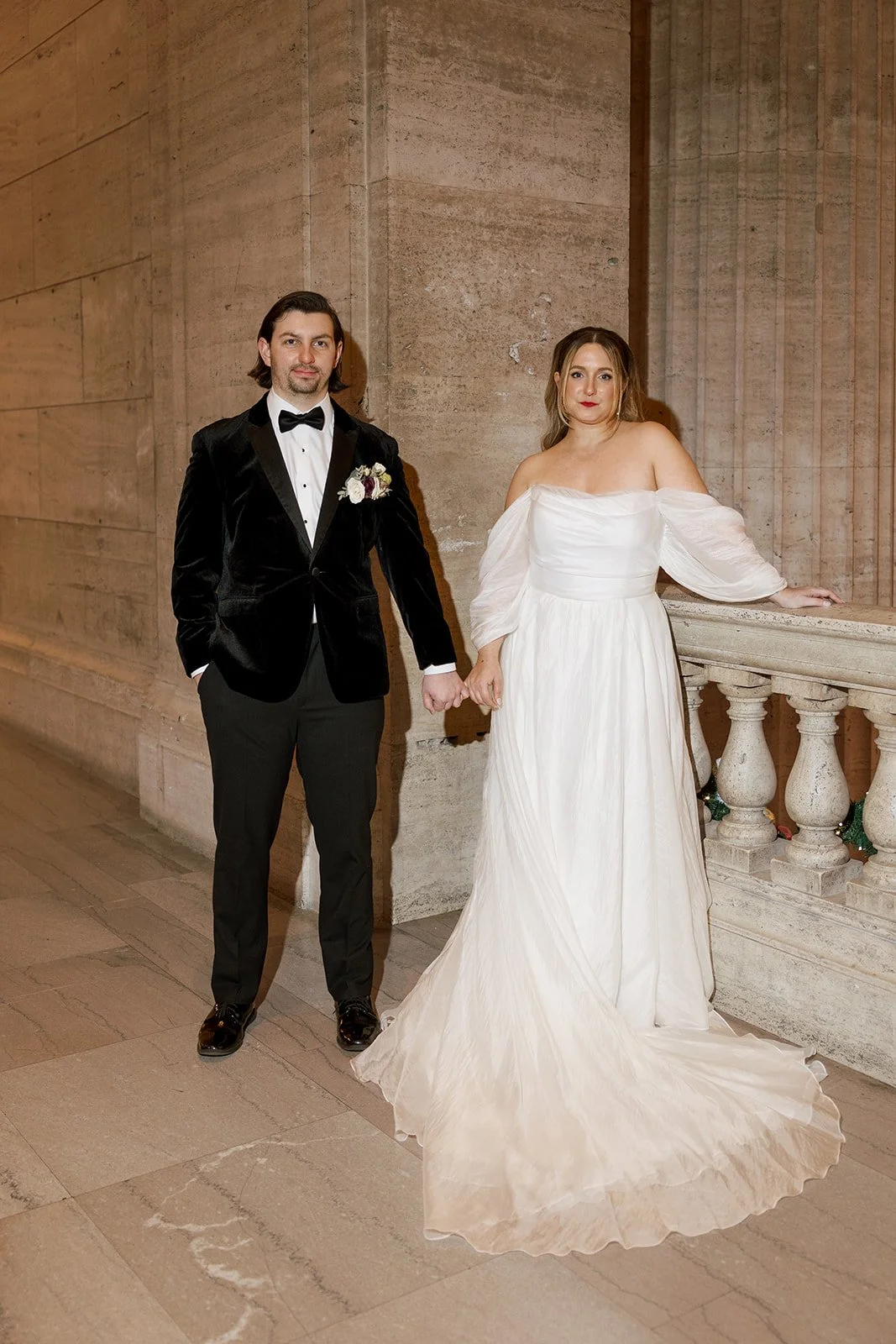 Bride and groom holding hands leaning on pillars serious at Union Station in Chicago
