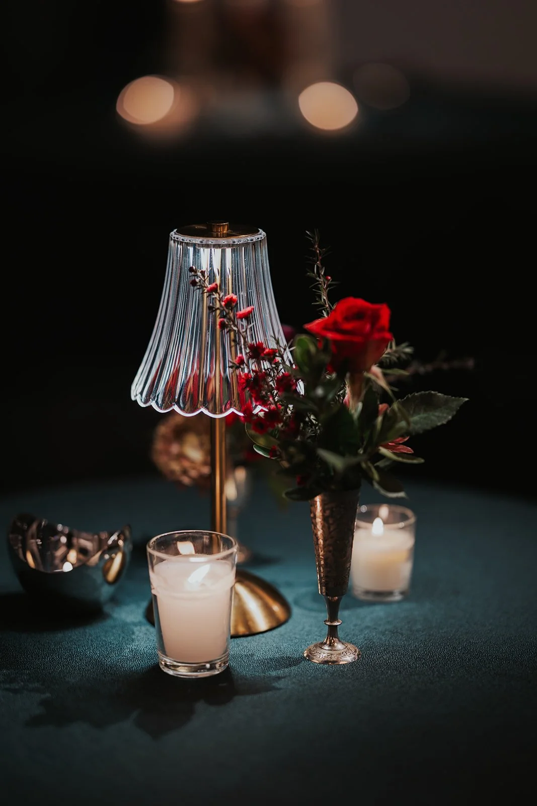 closeup of wedding reception table with lamp and red flowers