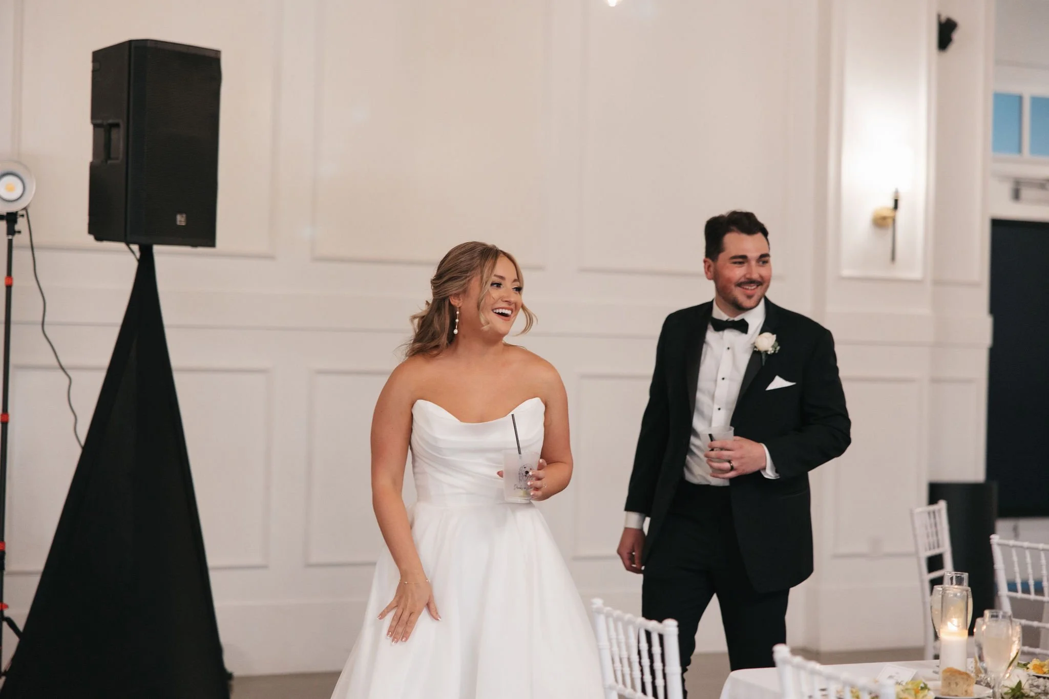 Bride and groom smiling while walking through their reception room seeing everything
