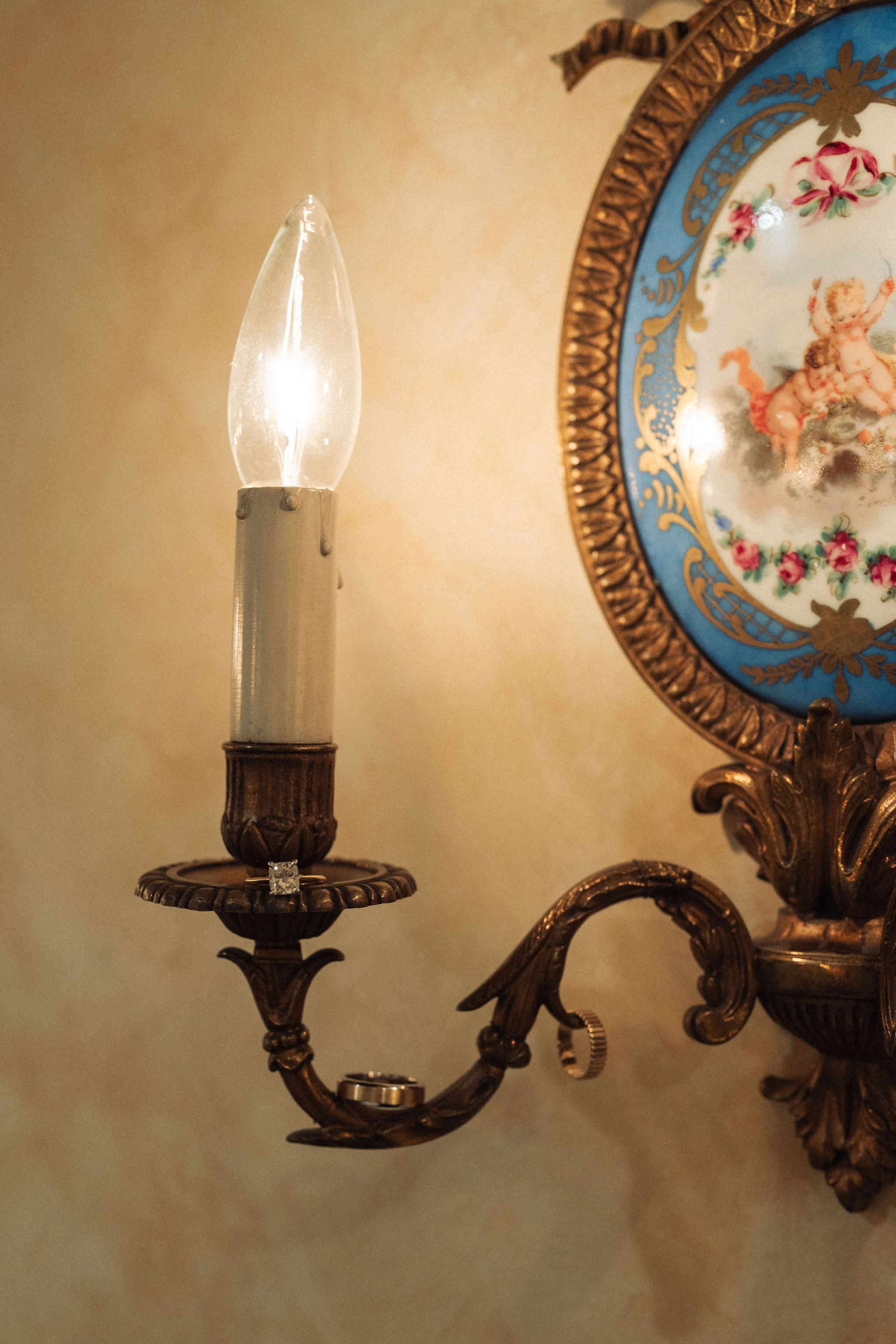 3 wedding rings hanging and sitting in different places on a close up of candle bulbs hanging on walls