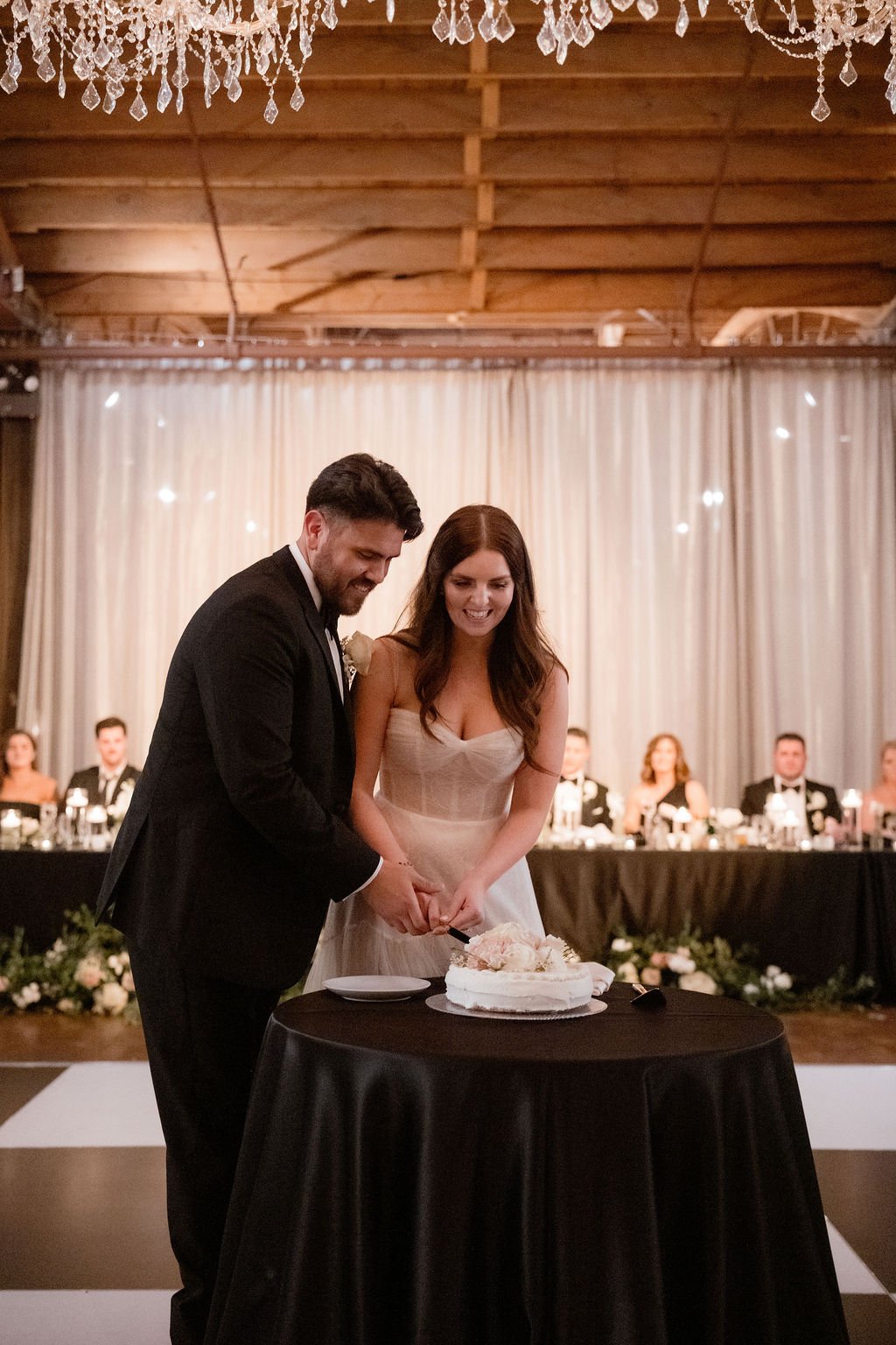 Bride and groom cutting cake on dance floor at wedding reception