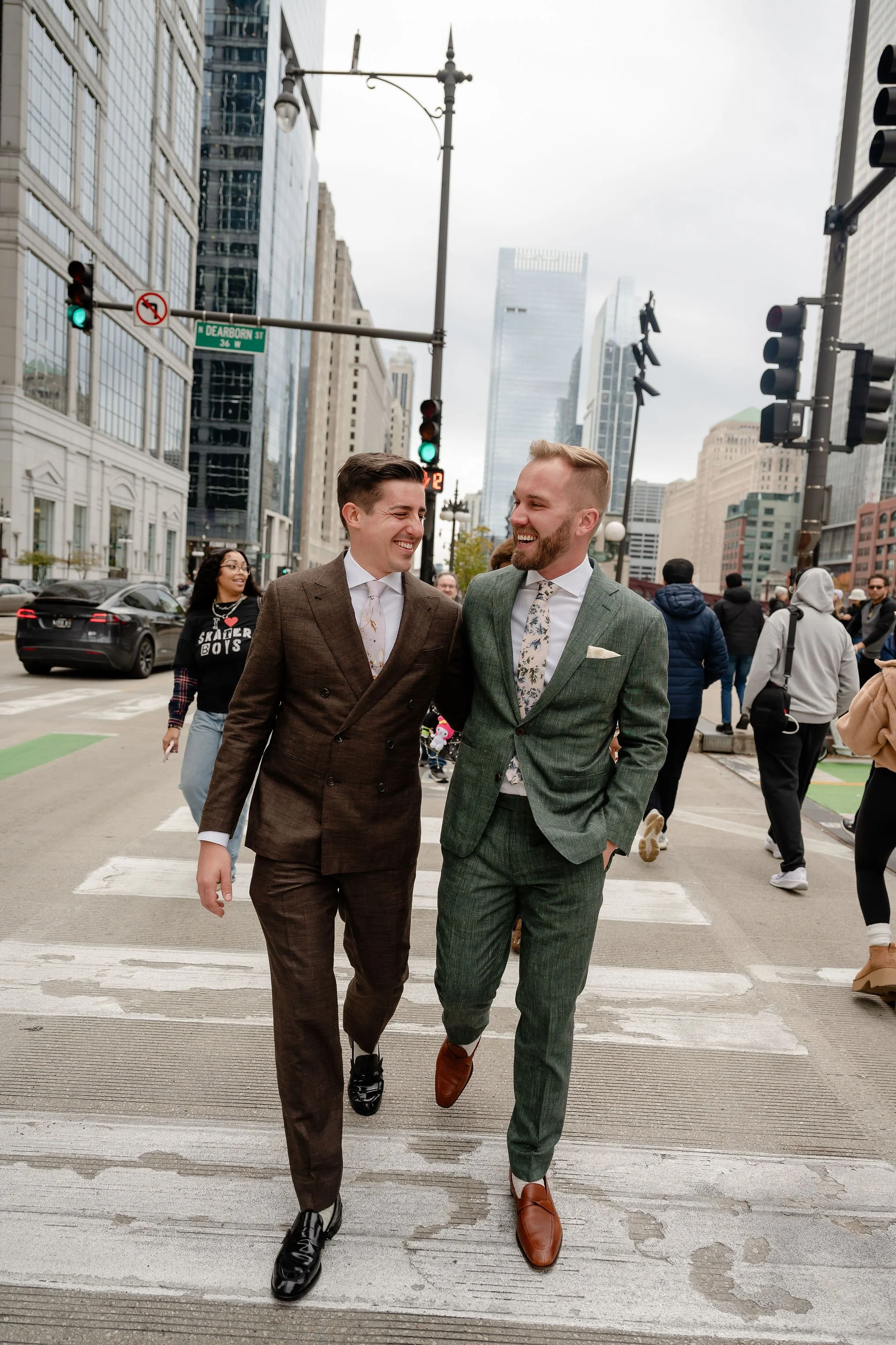Two grooms walking on crosswalk in Chicago streets looking at each other and smiling