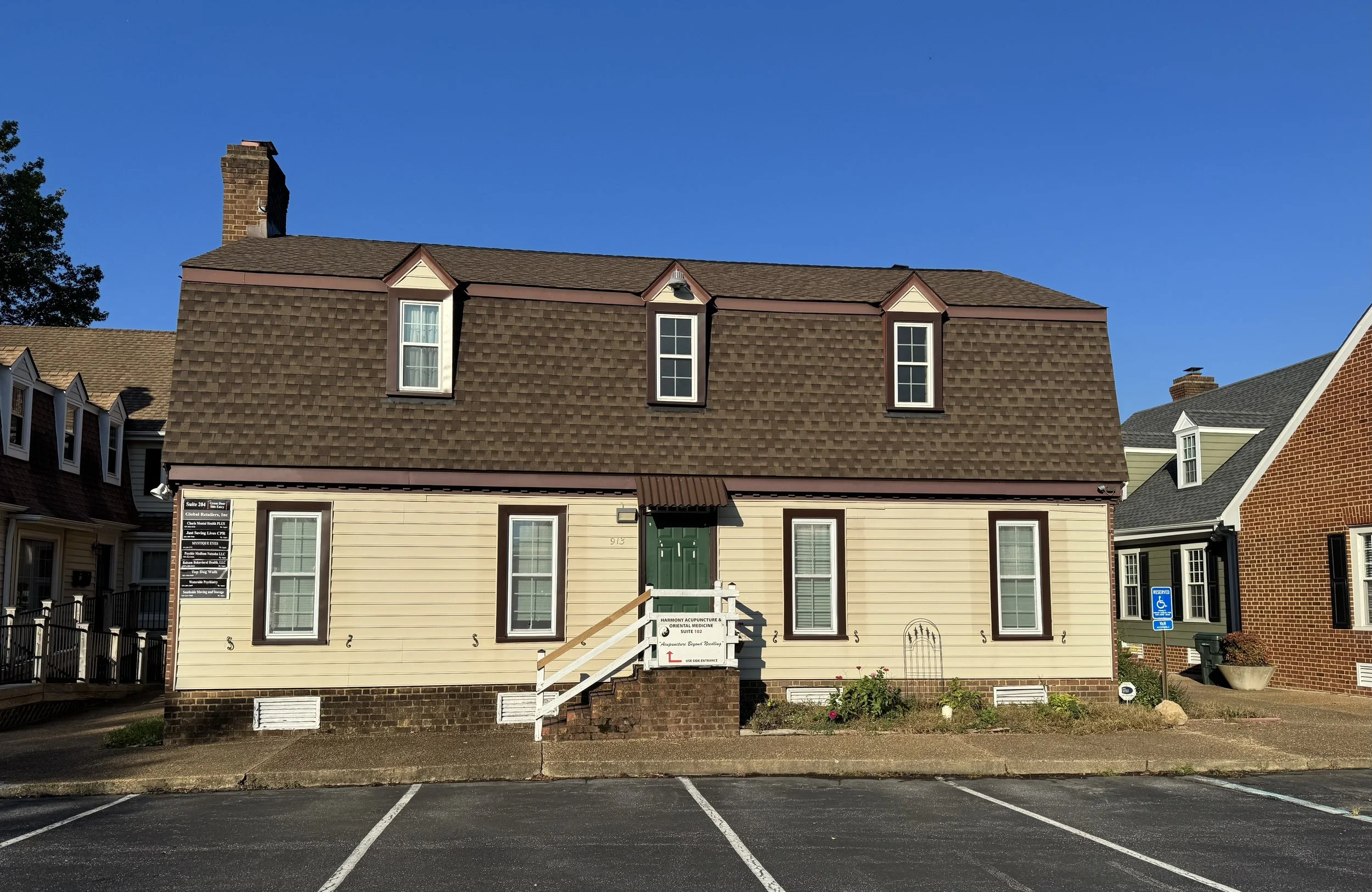 Front view of Psychic Medium Natasha LLC office building: a two-story tan building with a brown roof and a green door at 913 First Colonial Road, Suite 202E in Virginia Beach, Virginia.