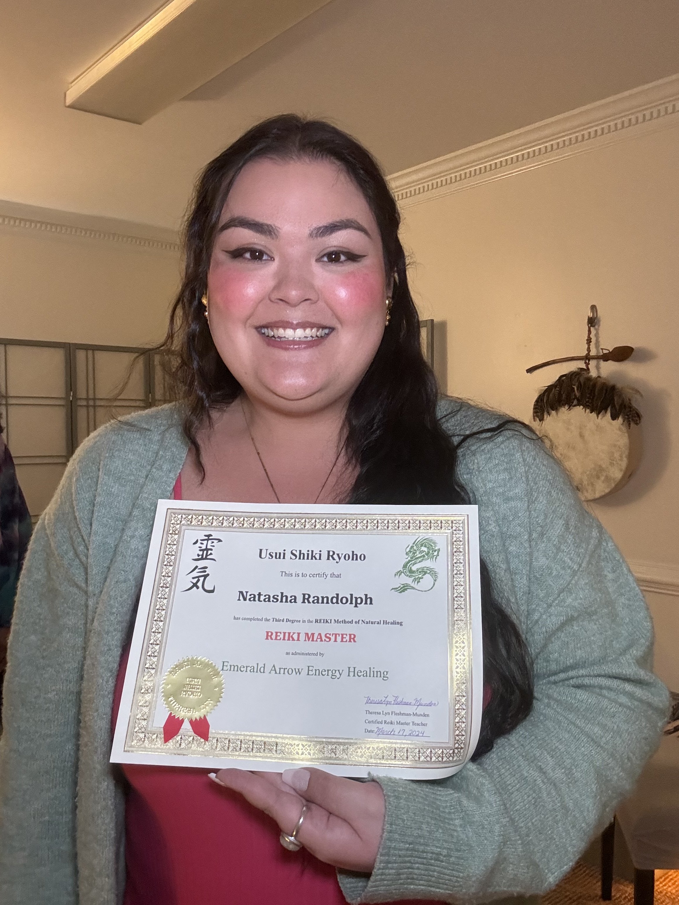 Portrait of Natasha smiling and proudly holding her official Reiki Master certification against her chest.

As a Reiki Master, Natasha has undergone advanced training and attunements, allowing her to channel Reiki energy at a higher level and guide o