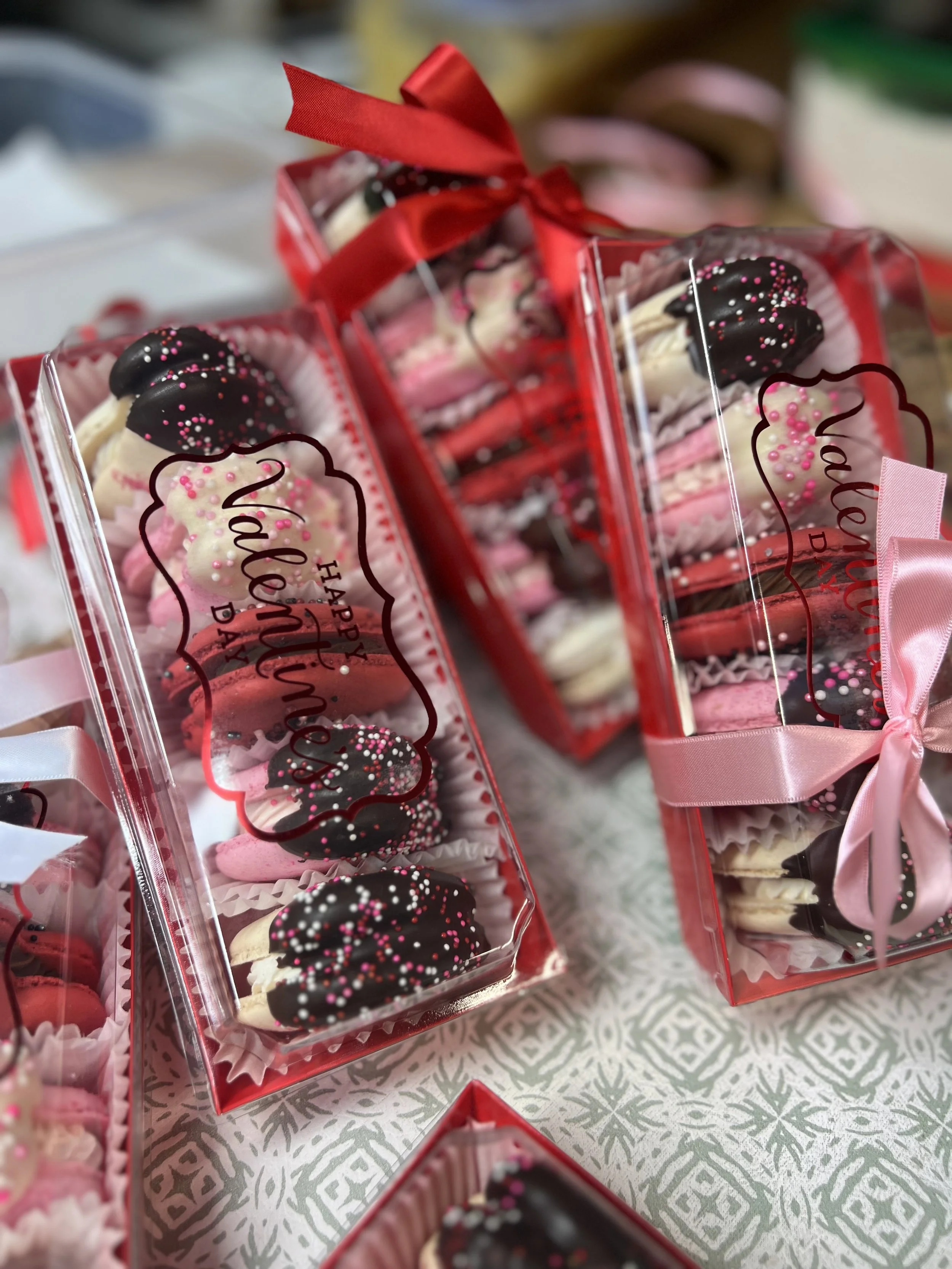 Gift boxes filled with pink and white cupcakes topped with chocolate, pink, and white sprinkles, decorated with pink and red ribbons.