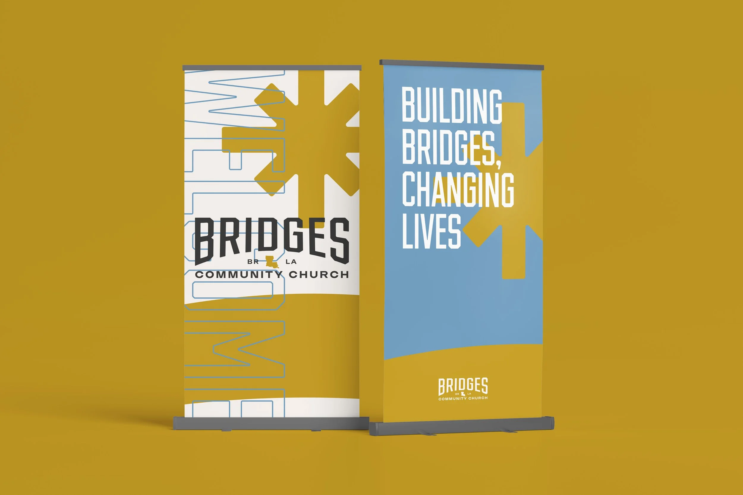 Two roll-up banners for Bridges Community Church, with one showing geometric design and the other displaying the slogan 'Building Bridges, Changing Lives'.