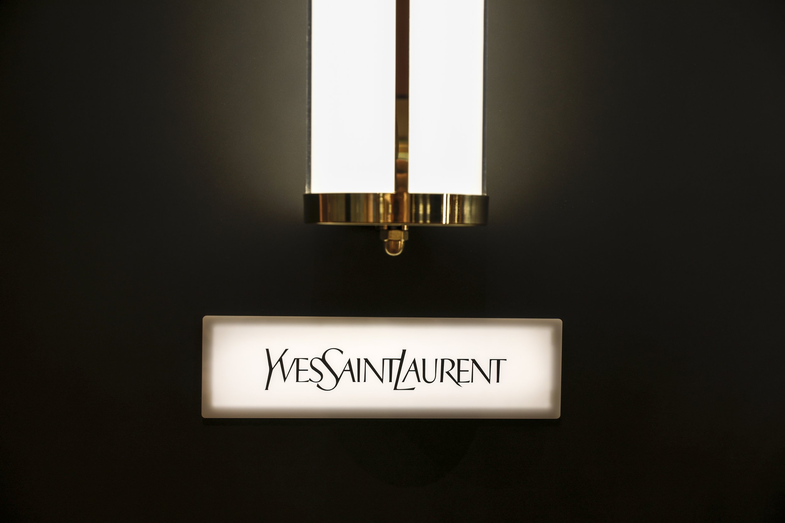 Brass wall lamp above the Yves Saint Laurent counter, designed for Boozt.com's store