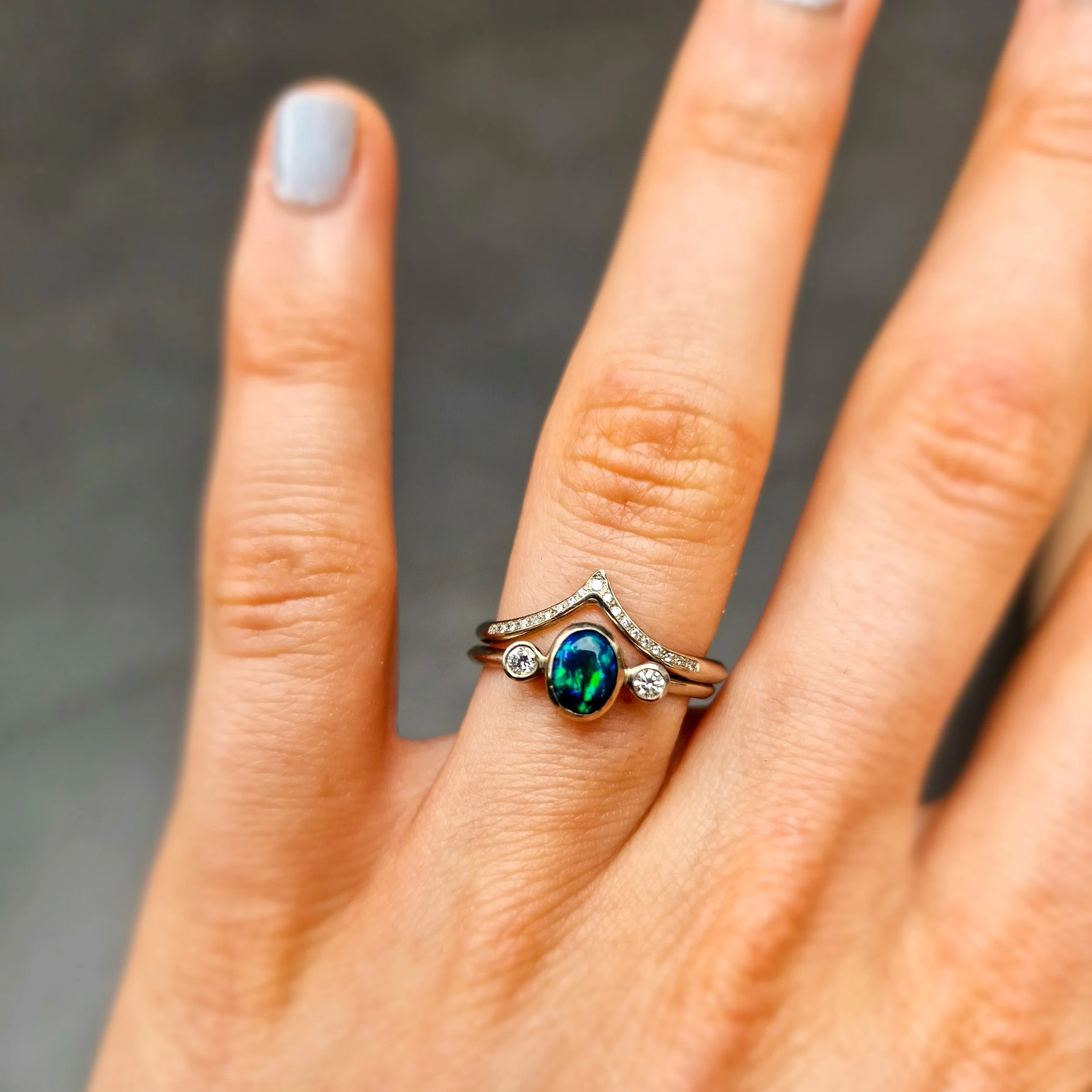 an 18ct white gold set of rings, one wishbone shape with pave set diamonds, the other a traditional triology with a black opal flanked on each side with a diamond