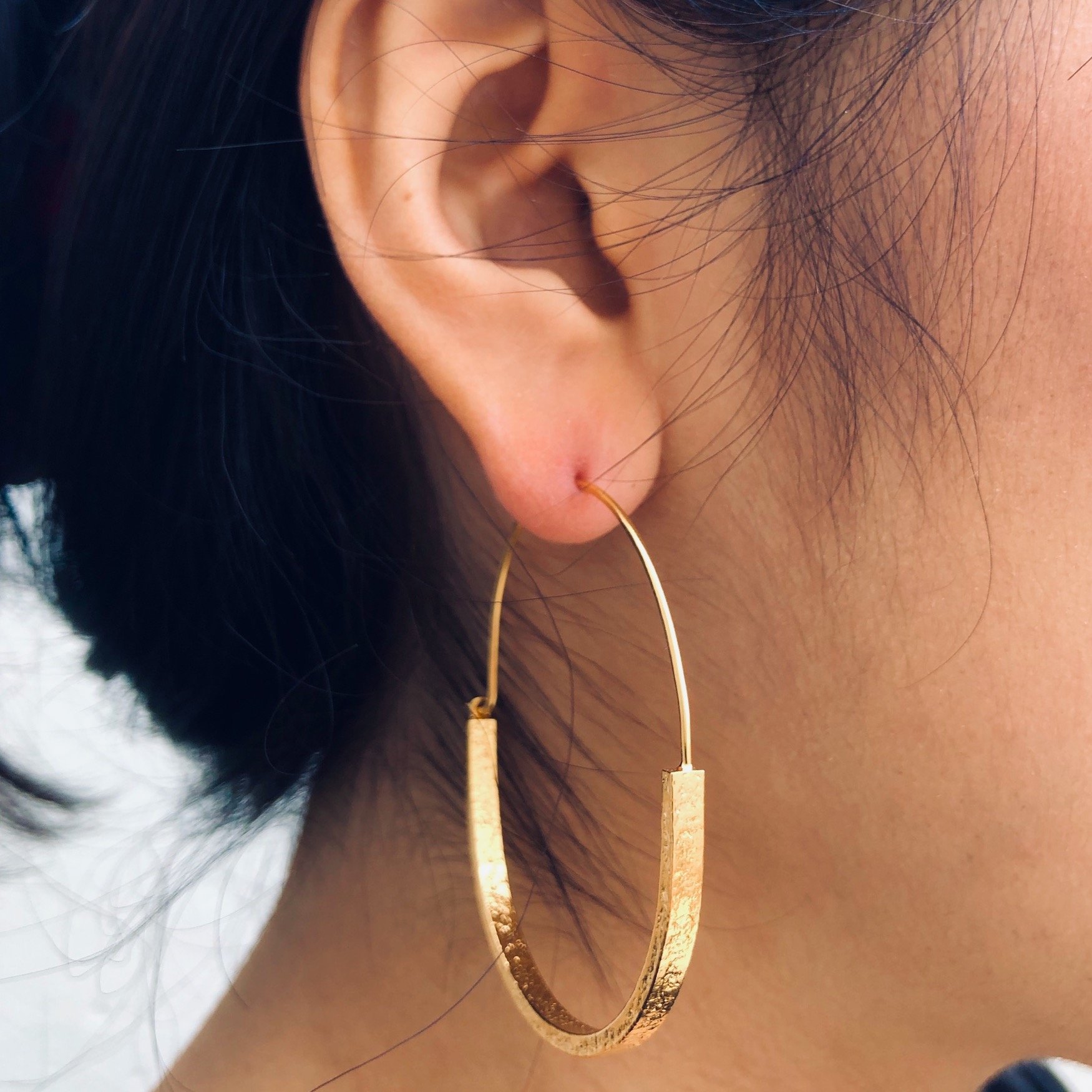 woman wearing gold plated contemporary large hoop earrings
