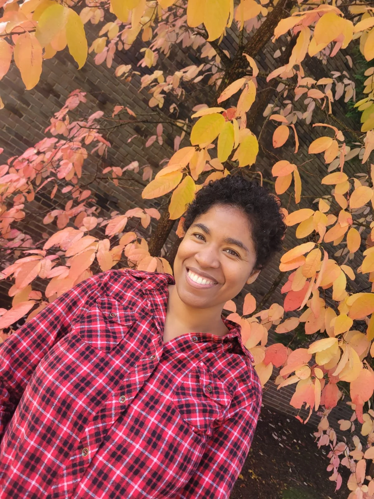 Mahajoy wearing red plaid shirt in front of yellow tree