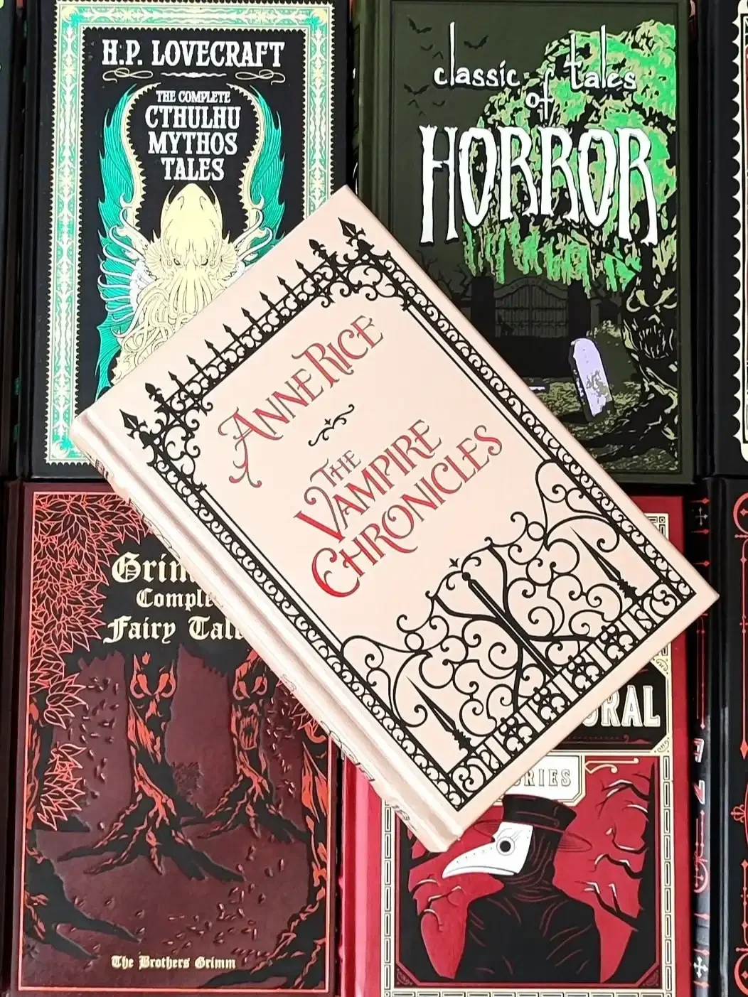 leatherbound edition of the Vampire Chronicles by Anne Rice, featuring a gray cover with an ornate black fence and gate, laying on top of 4 other classic horror books