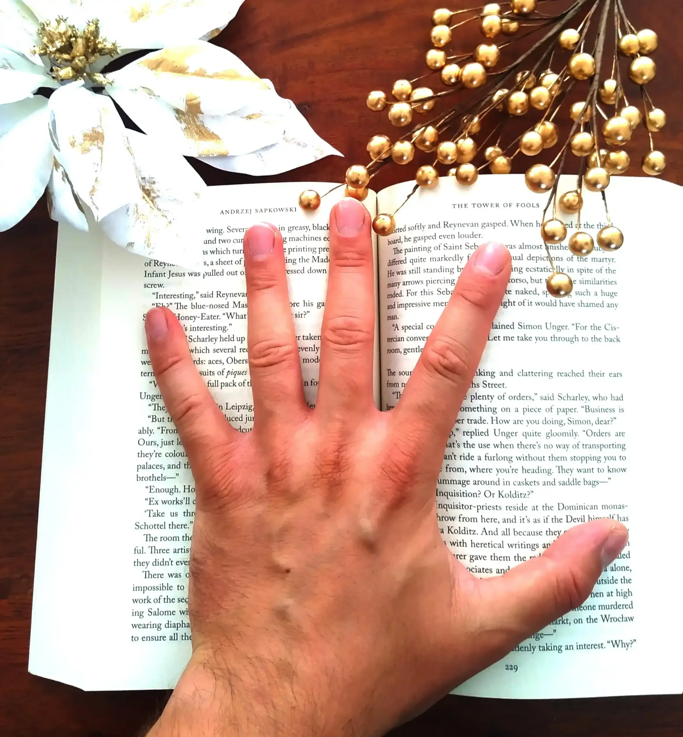 A reader's hand pressing down on an open page of a fantasy novel, symbolizing a reading slump and the inability to focus on the text.
