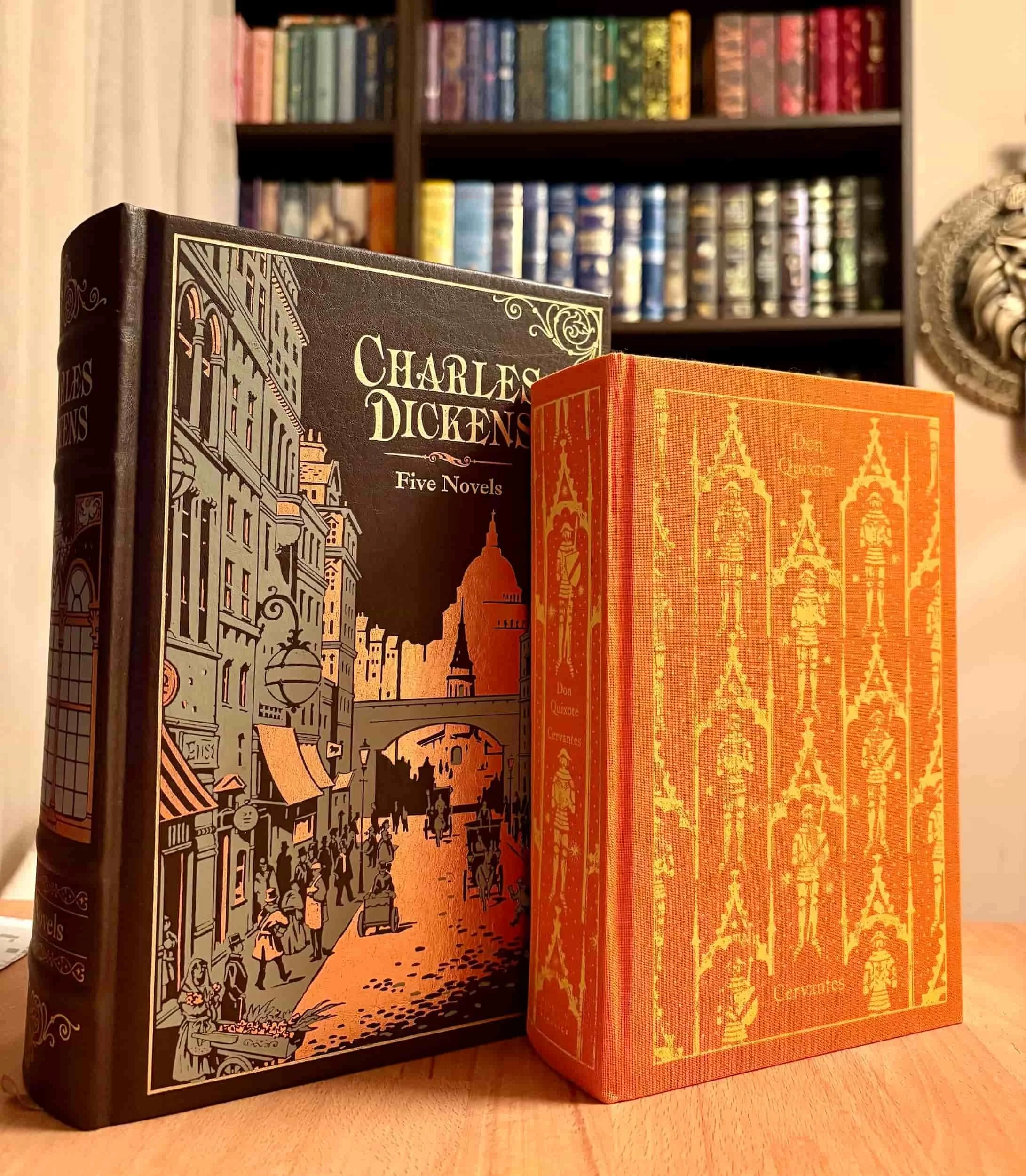 Foundational classic literature books Don Quixote and A Tale of Two Cities next to a coffee cup.