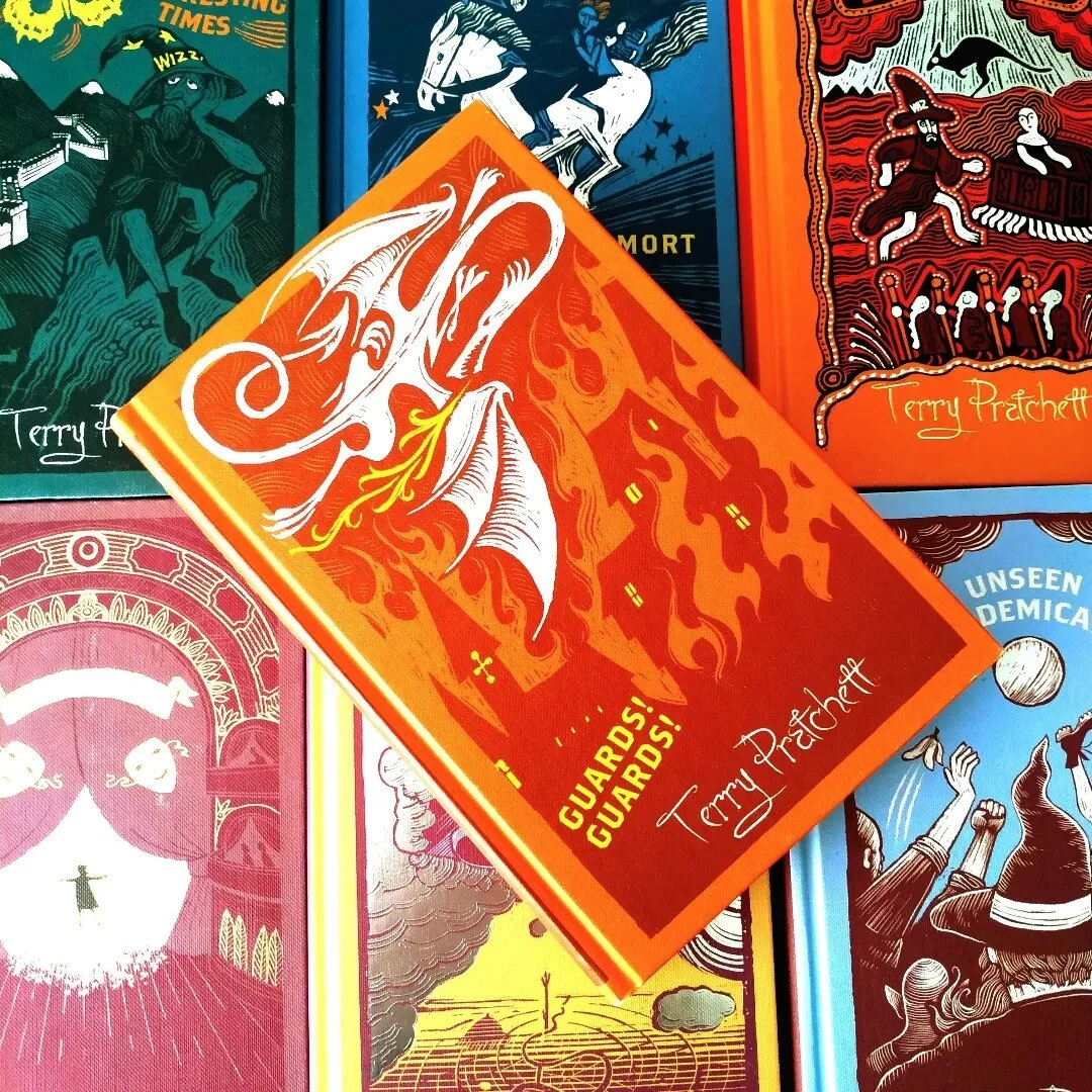 Orange cloth hardcover edition of Guards! Guards! by Terry Pratchett featuring a gold dragon illustration on the cover.