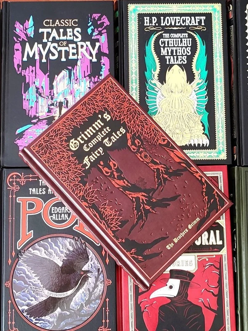 Red leatherbound edition of Grimm's Complete Fairy Tales laying on top of 4 other classic horror books 2026