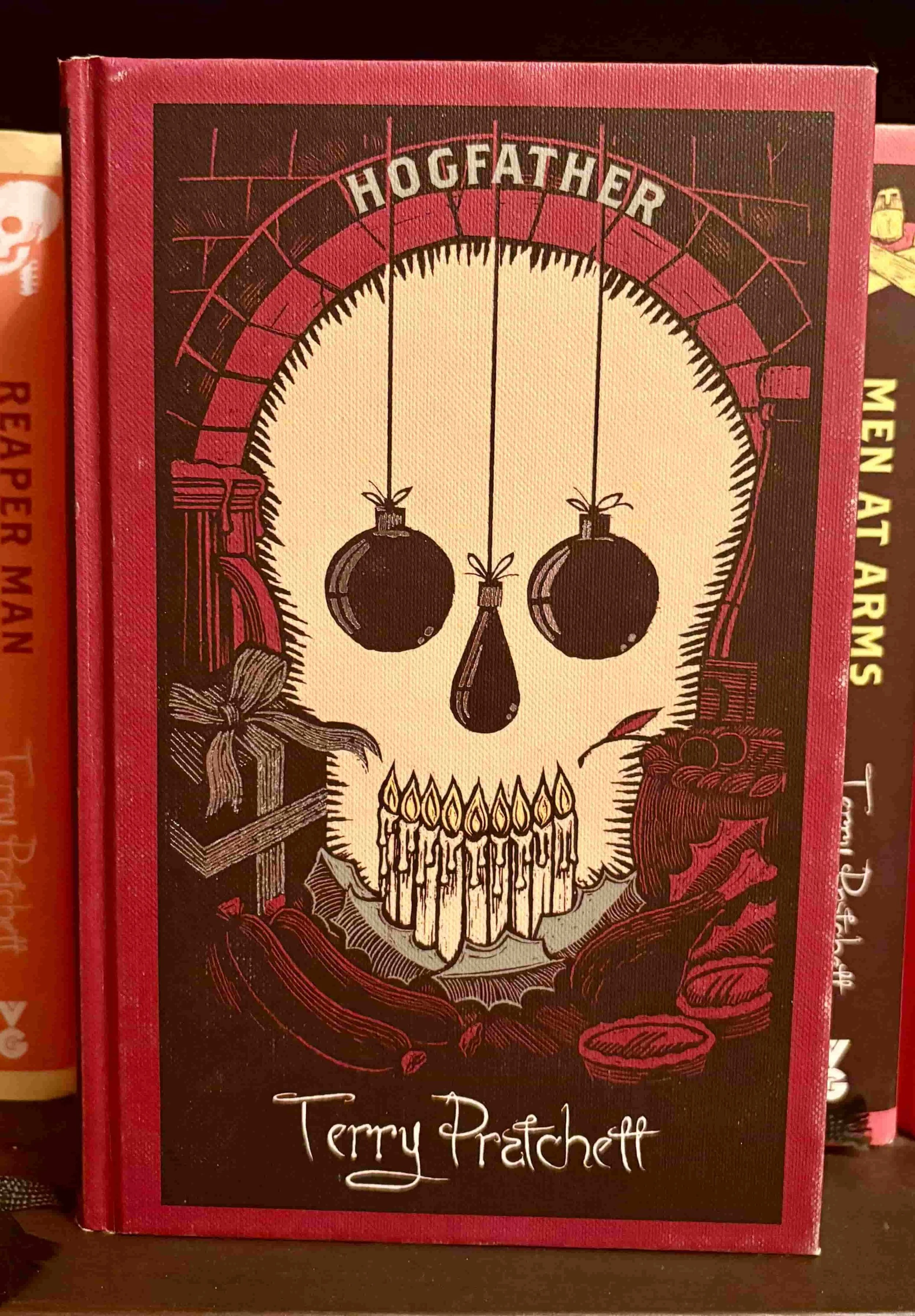 The dark cover of Hogfather by Terry Pratchett, featuring a skull and festive holiday themes.