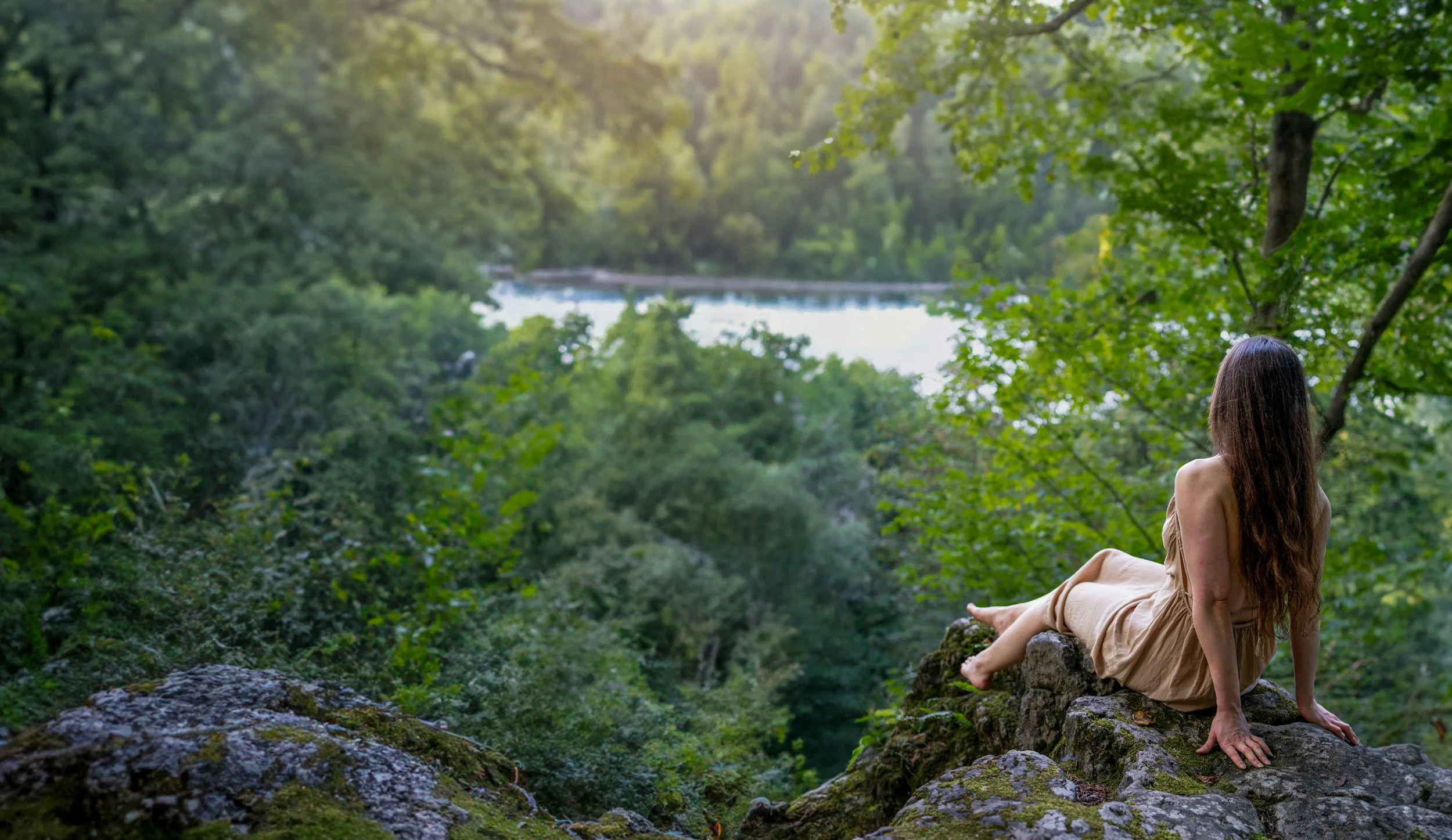 Woman sitting in nature with hand to heart, symbolizing burnout recovery and somatic support for strong women.