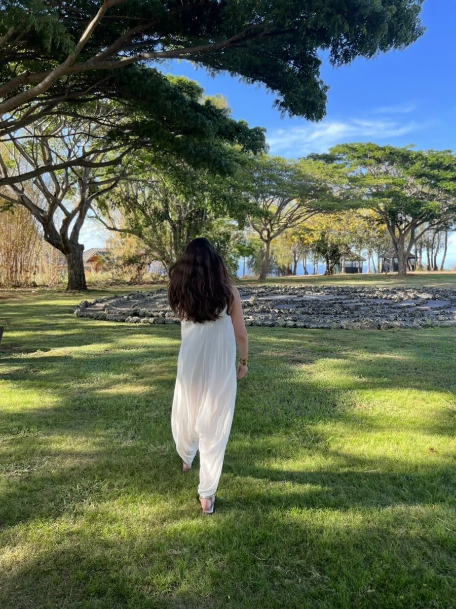 Woman with her back to the camera looking at the labyrinth, symbolizing identity transitions and the healing journey.