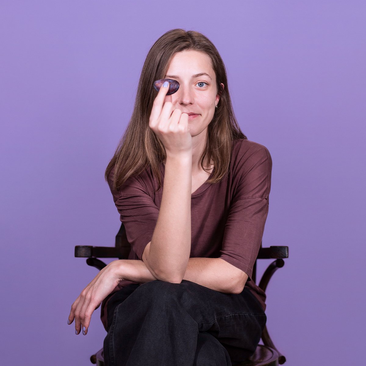 Maya Ciubotaru, the brand identity designer behind Plumline, holding a small plum against a purple studio backdrop.
