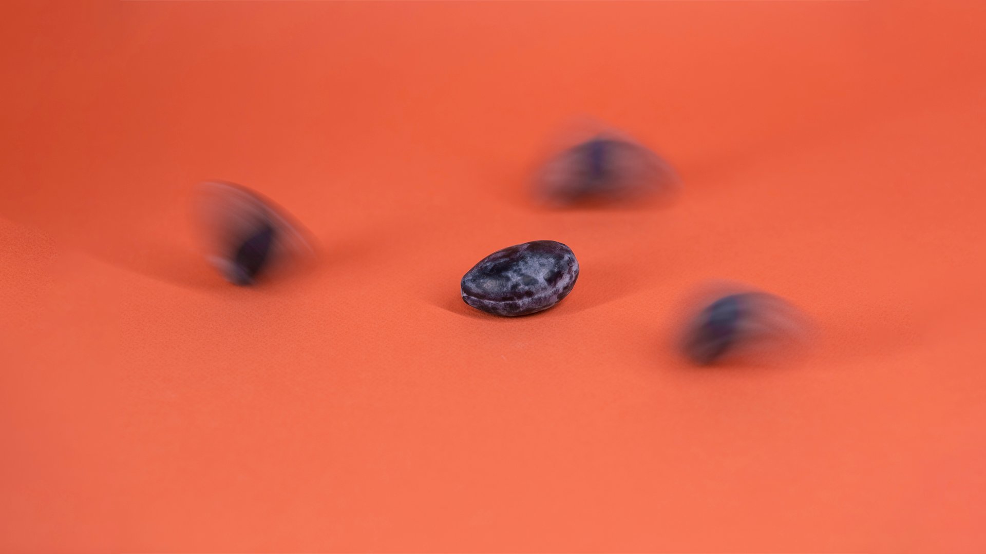 Plums moving across an orange shape against a lavender background, introducing Plumline's playful visual identity.