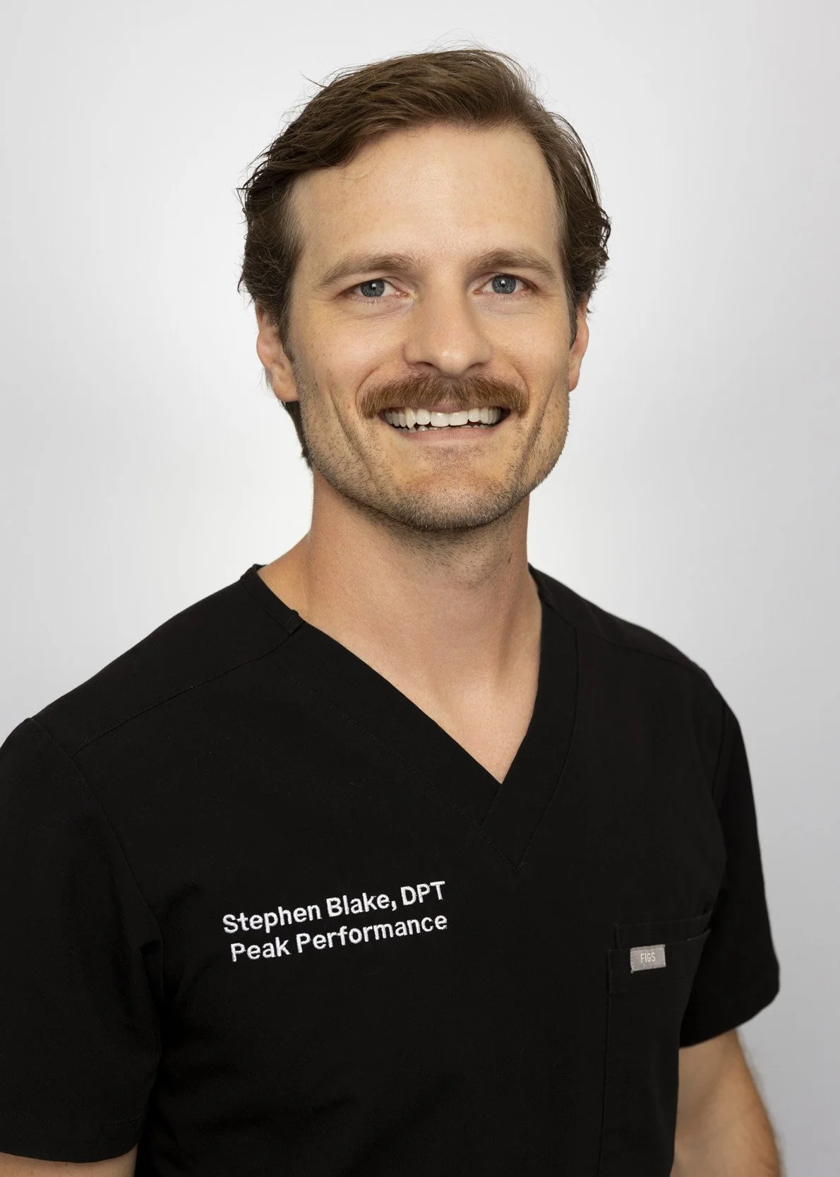 Man in black scrubs sits on blue couch