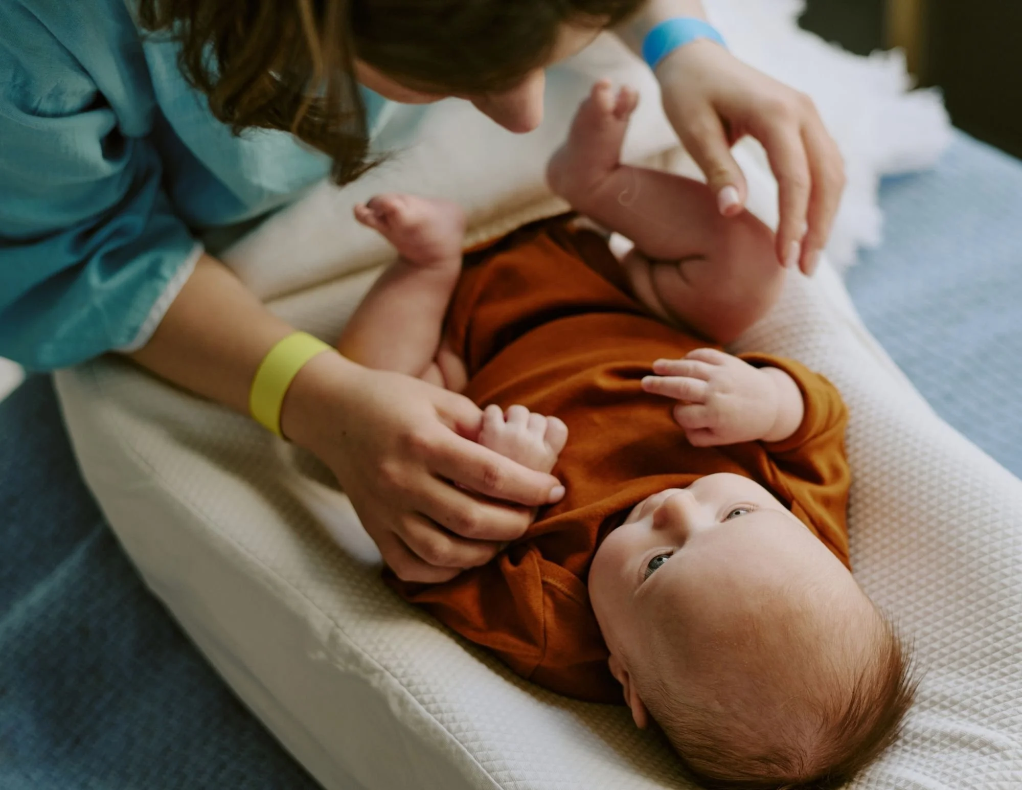 Person caressing a baby lying on a changing pad.