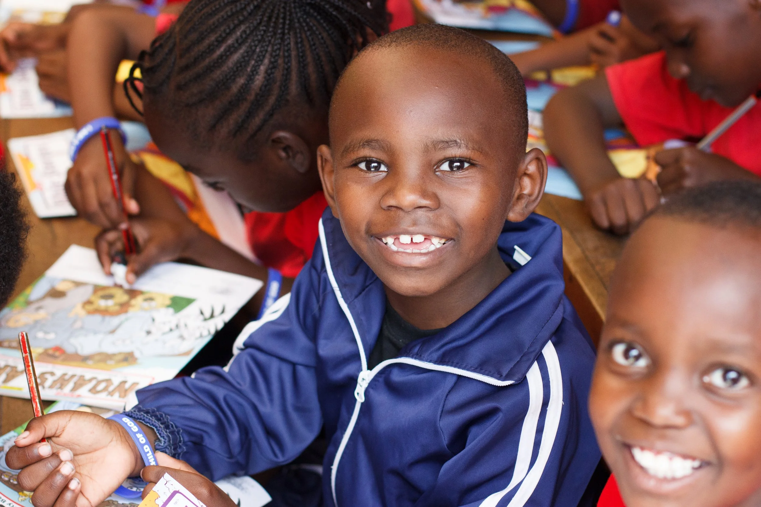 Students at Petra School in Kenya smiling during a classroom lesson.