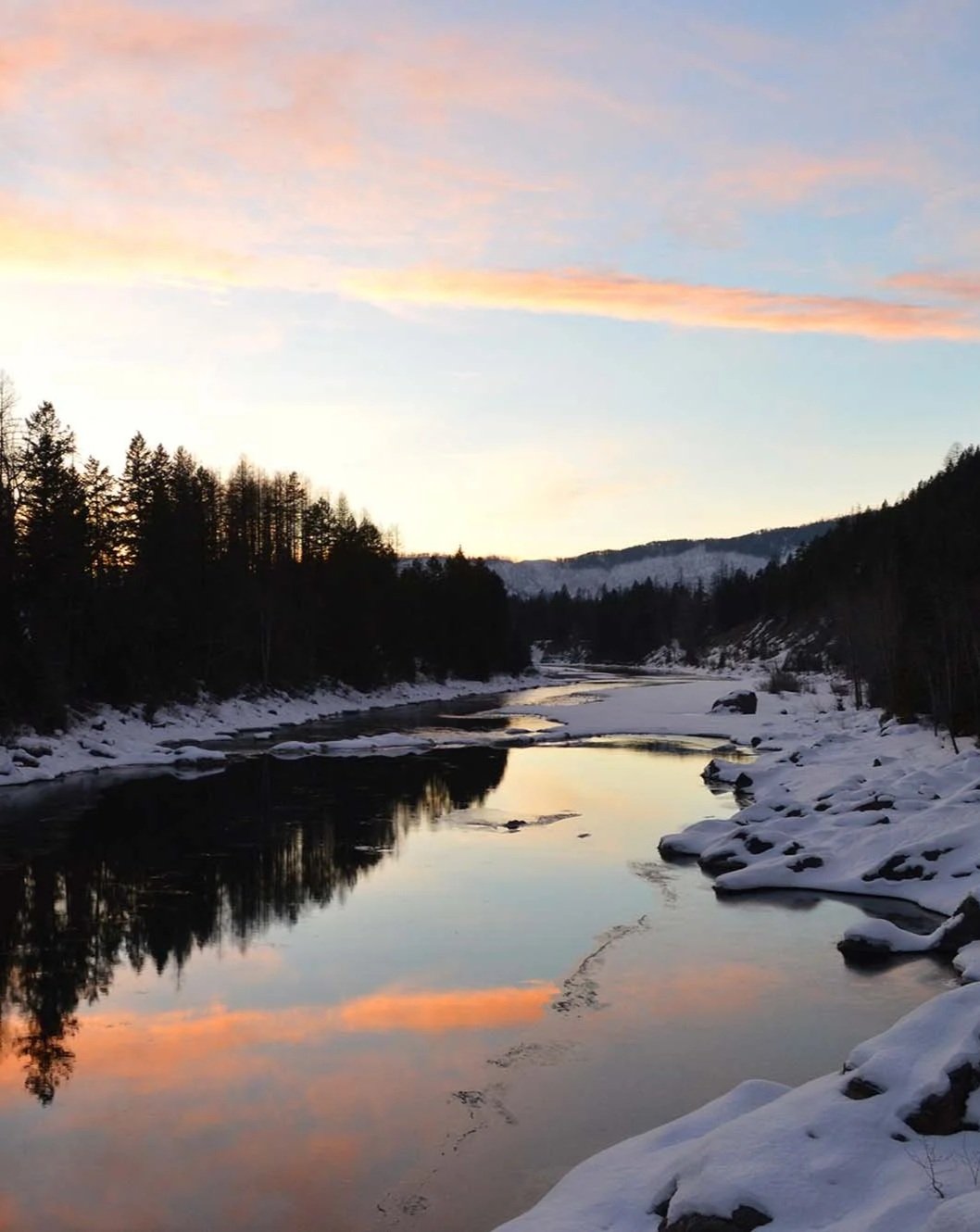 The Swan River in Bigfork, Montana at sunset in winter with snow on the ground