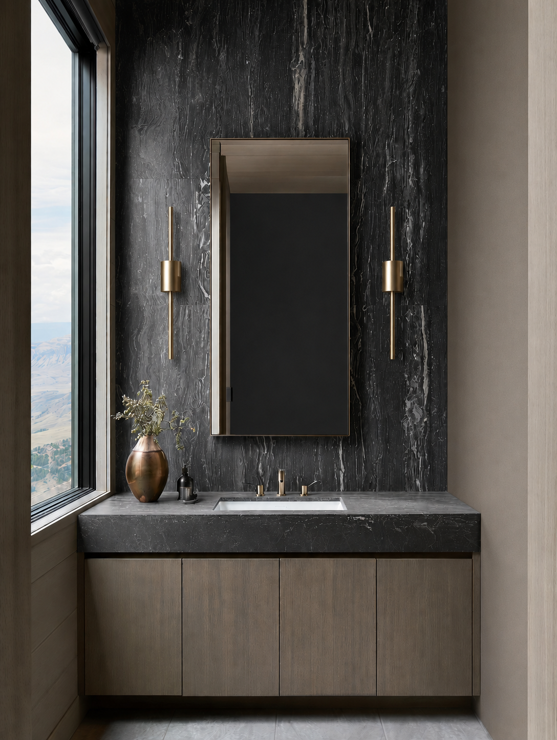 Luxurious powder room with black travertine slab backsplash, light oak vanity and large gold sconces