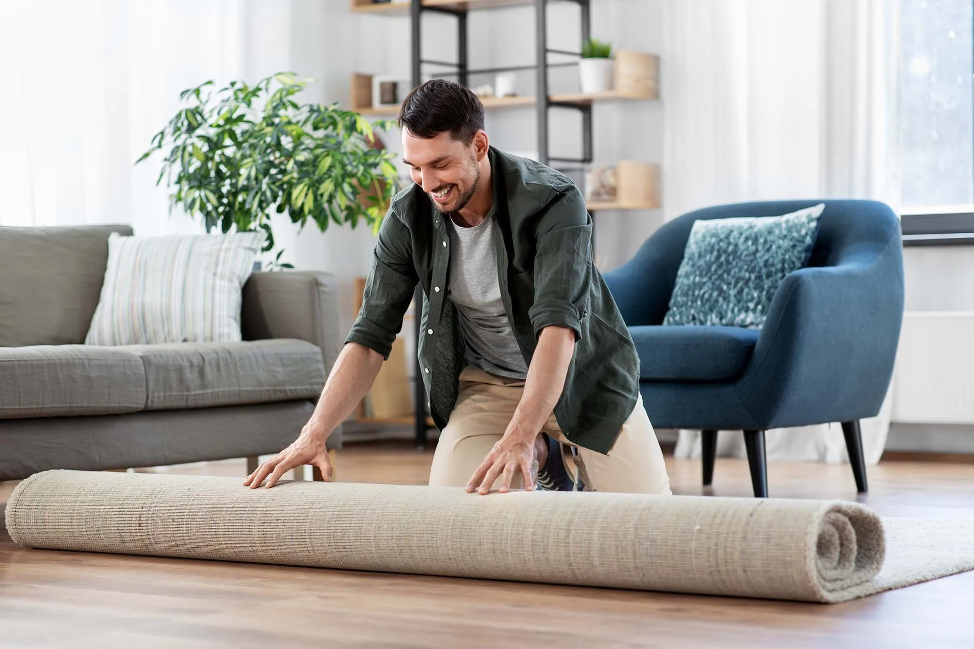 Man rolling out rug in professionally decorated living room