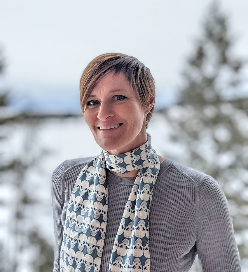 Headshot of female interior designer with short hair, standing in front of Whitefish Lake