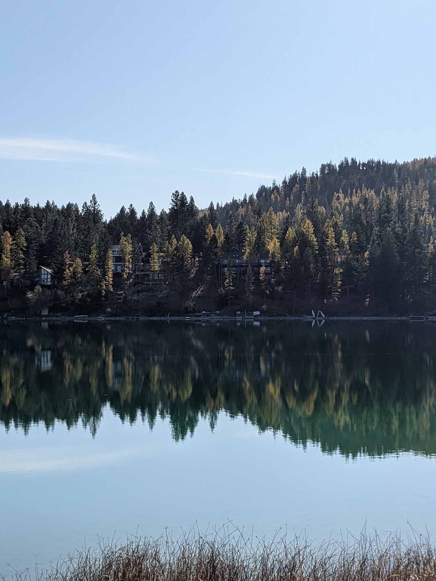 Foys Lake in Kalispell, Montana with forest and lakefront homes reflecting over still water