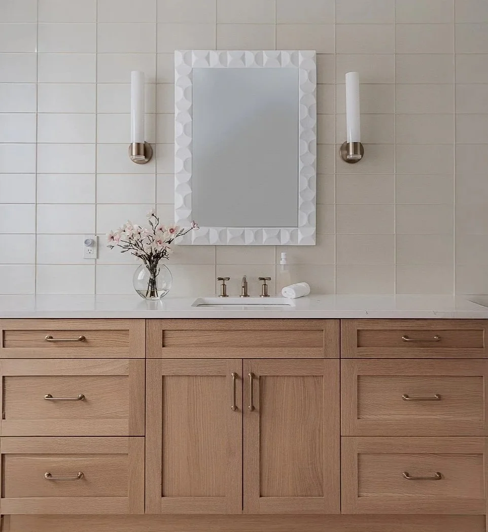 Primary bathroom vanity with white oak cabinets, champagne bronze fixtures and scalloped white mirror in the Flathead Lake House, a home designed by Daunt Designs in Bigfork, Montana