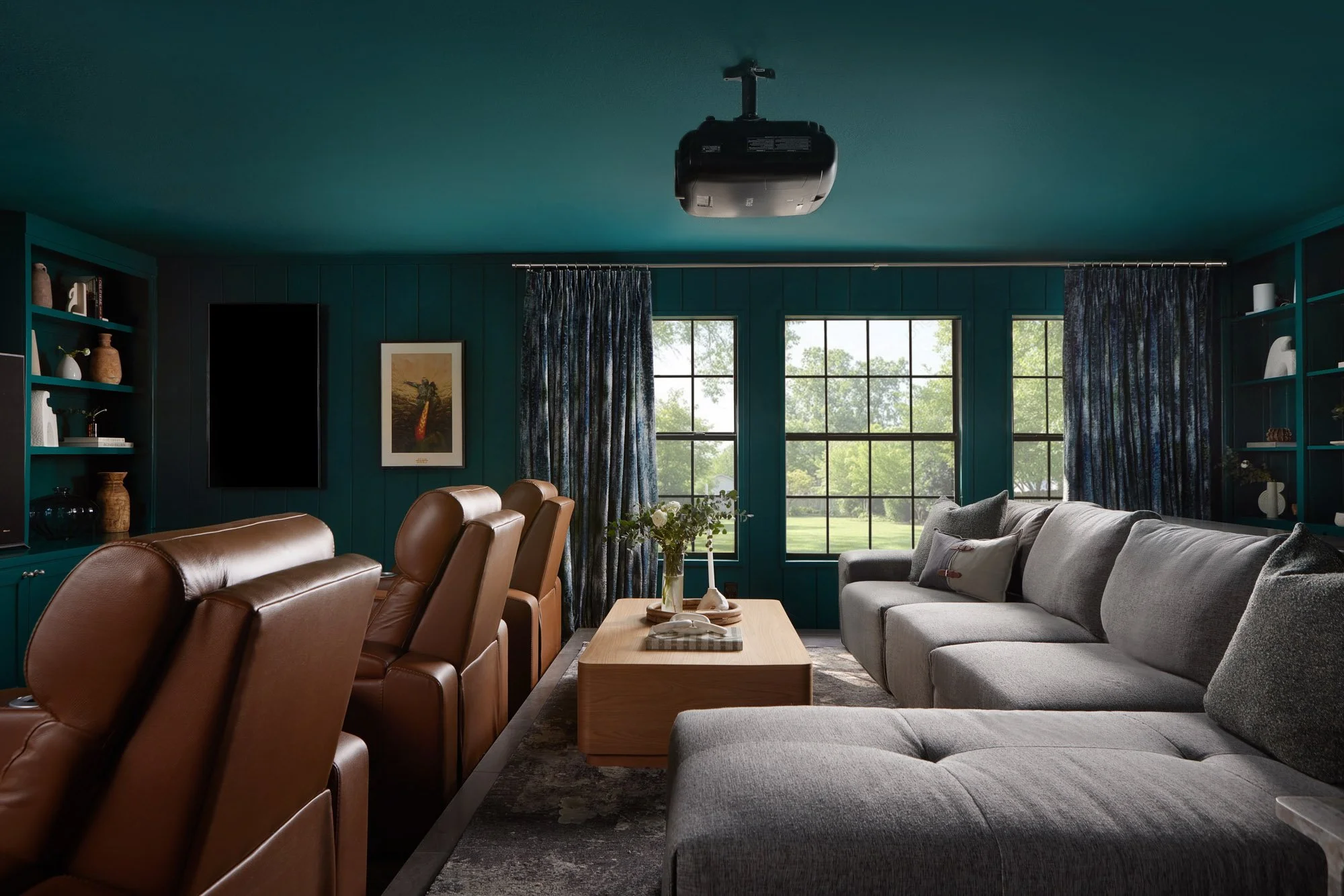 Dallas home theater featuring deep teal walls and ceiling, leather reclining theater seats, a gray sectional sofa, and custom window treatments designed by Paige Studio.